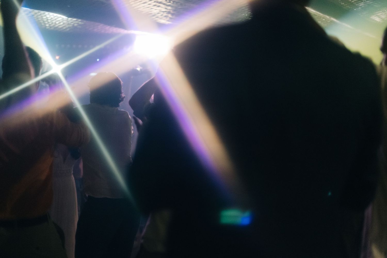 Dramatic light beams shine through a dark reception venue creating an atmospheric effect.