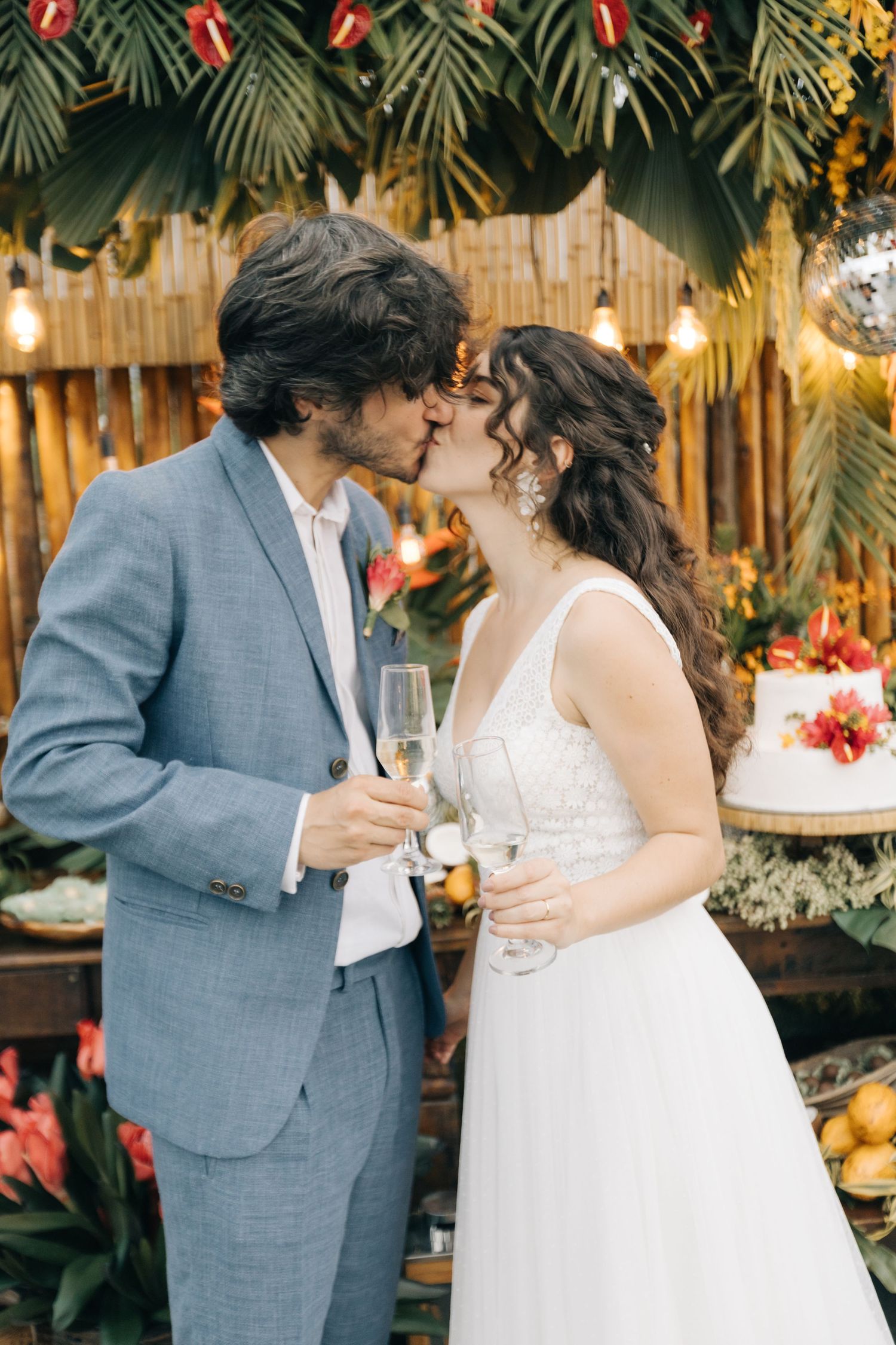 An intimate wedding moment captured with tropical foliage and warm lighting in the background.