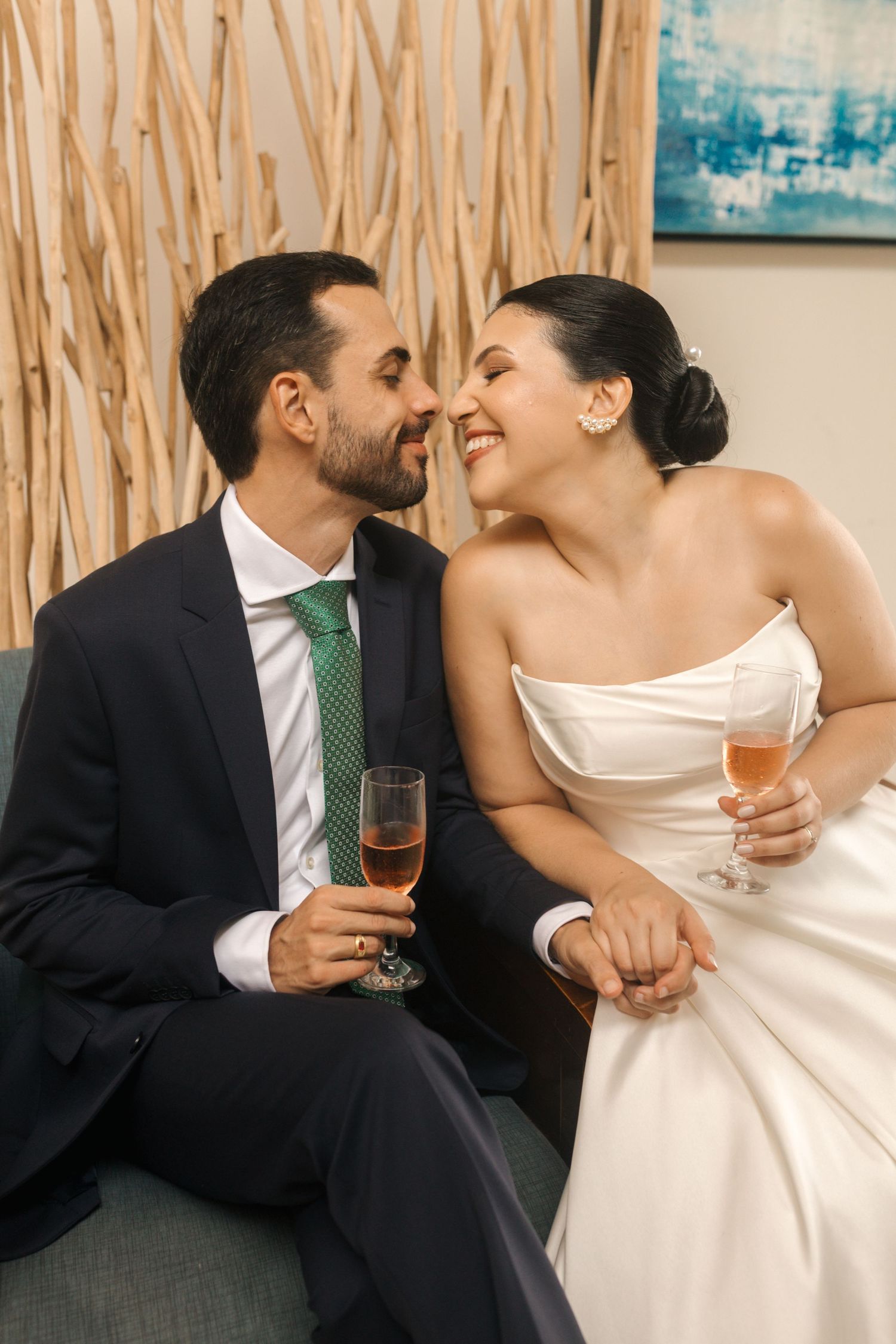 Newlyweds sharing an intimate moment while holding champagne glasses on a couch.