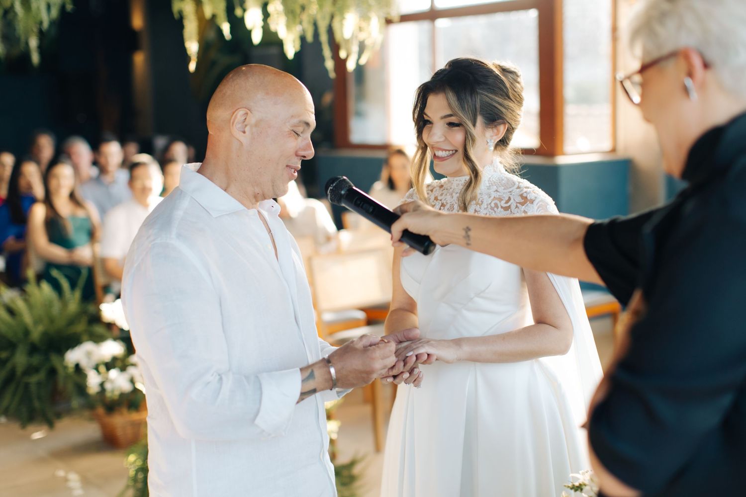 Wedding ceremony with couple exchanging vows under hanging floral decorations.