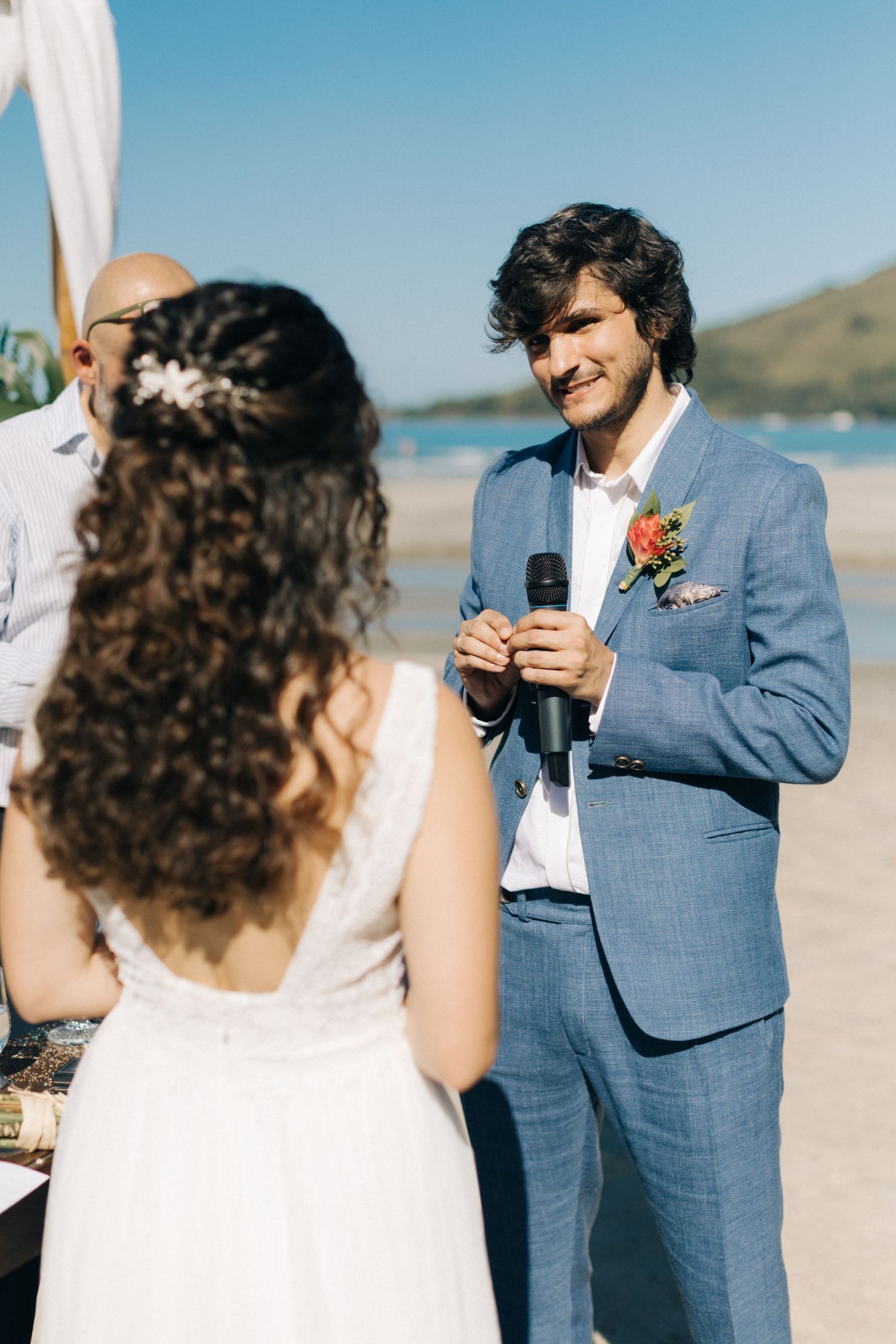 Couple exchanging vows during outdoor beach ceremony with ocean view.