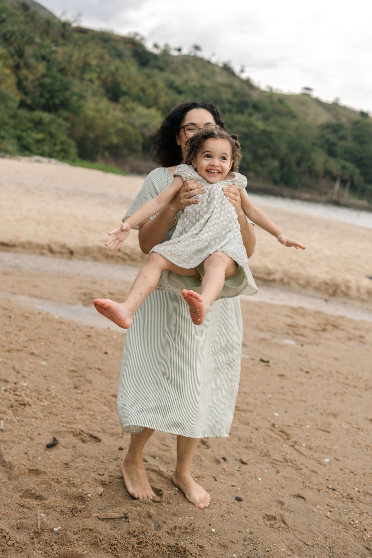 Joyful moment captured on a beach as a child is lifted high into the air.