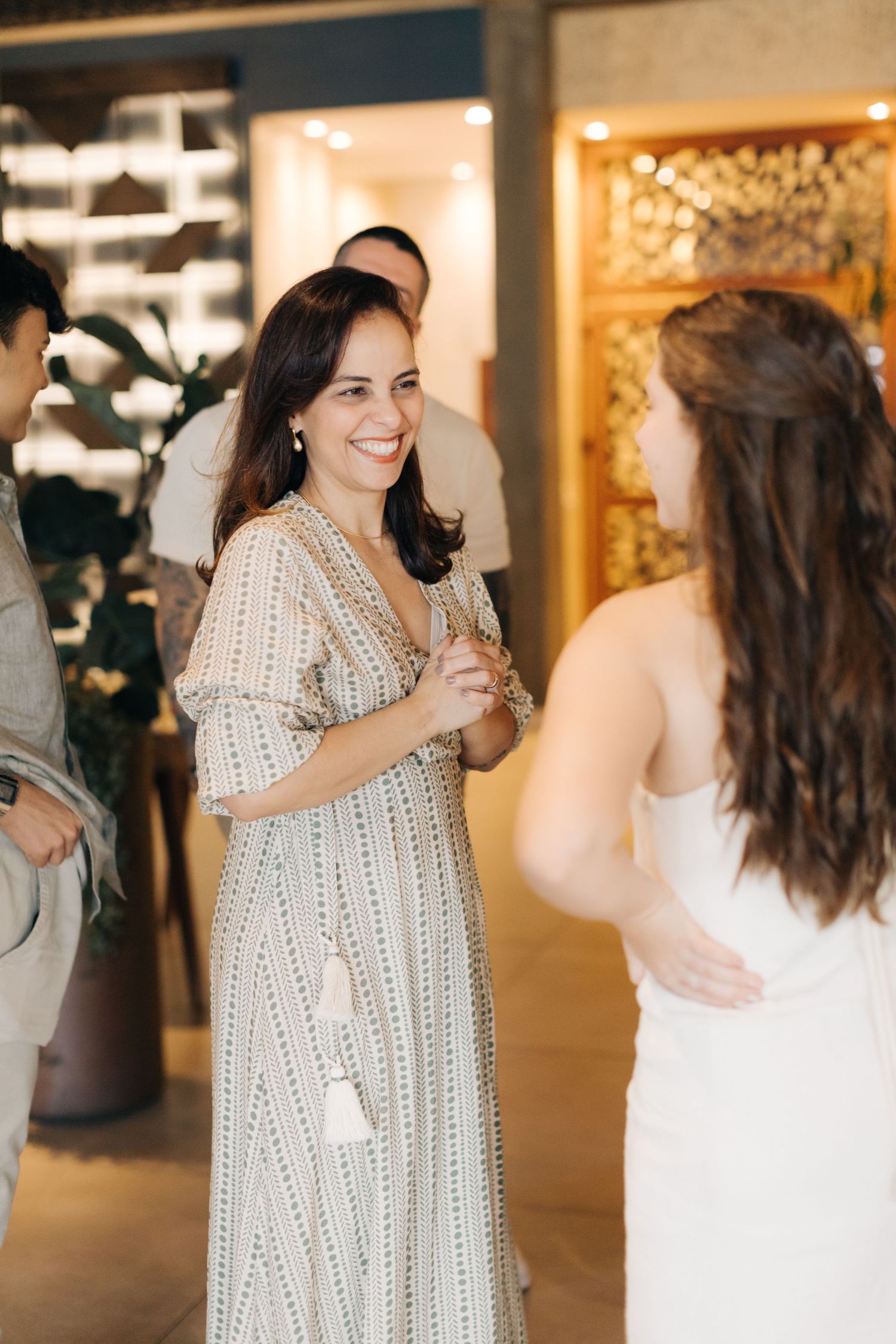 Two attendees in elegant dresses share a conversation at a formal event.