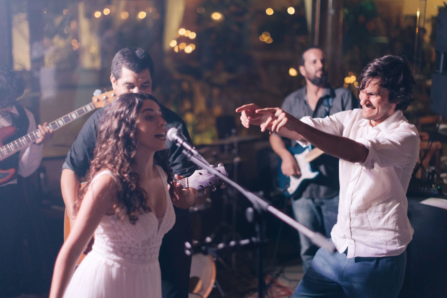 Live band performs at wedding reception with musicians and singer on stage.