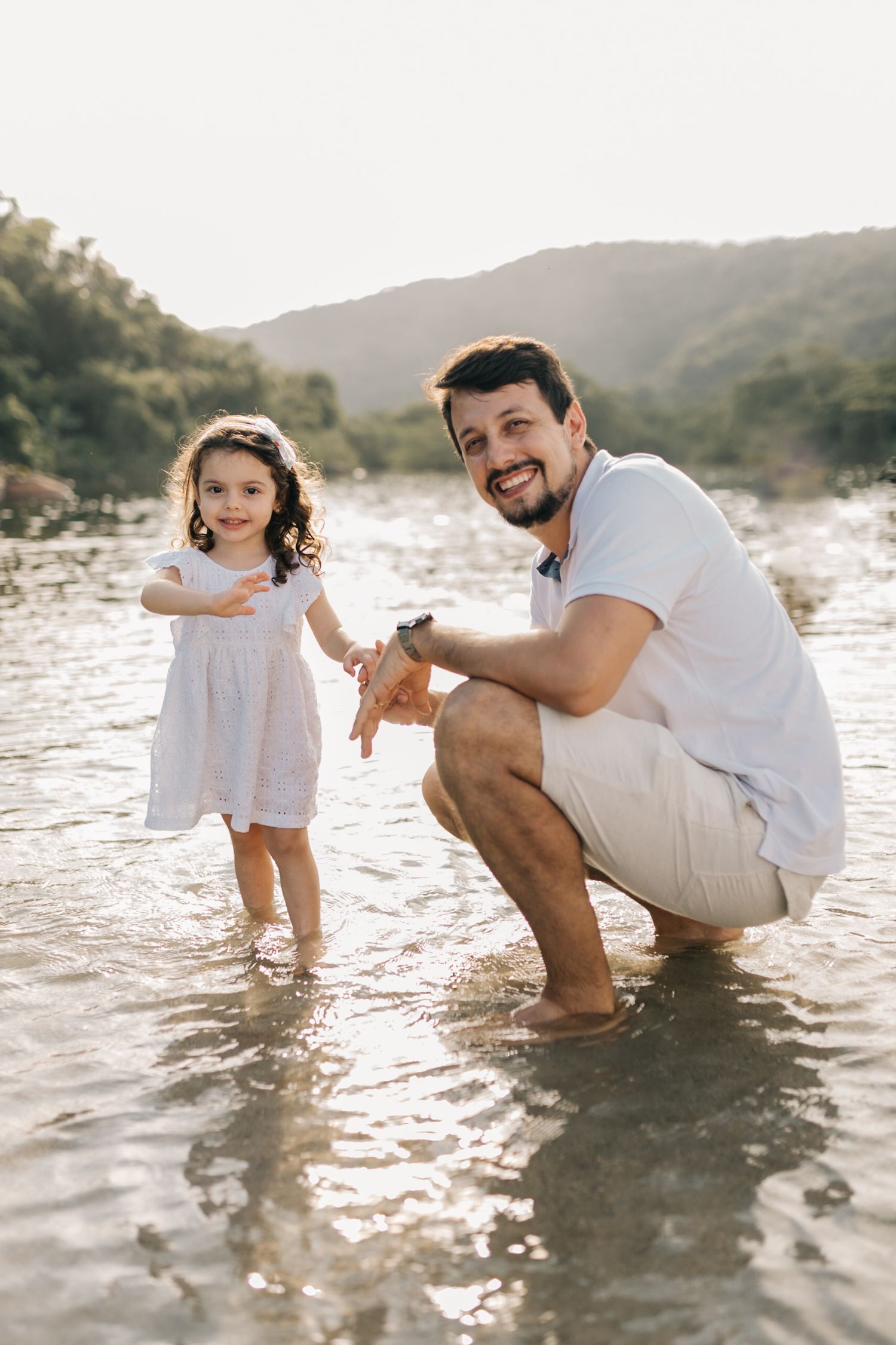 Family members playing and interacting in the ocean water at sunset.