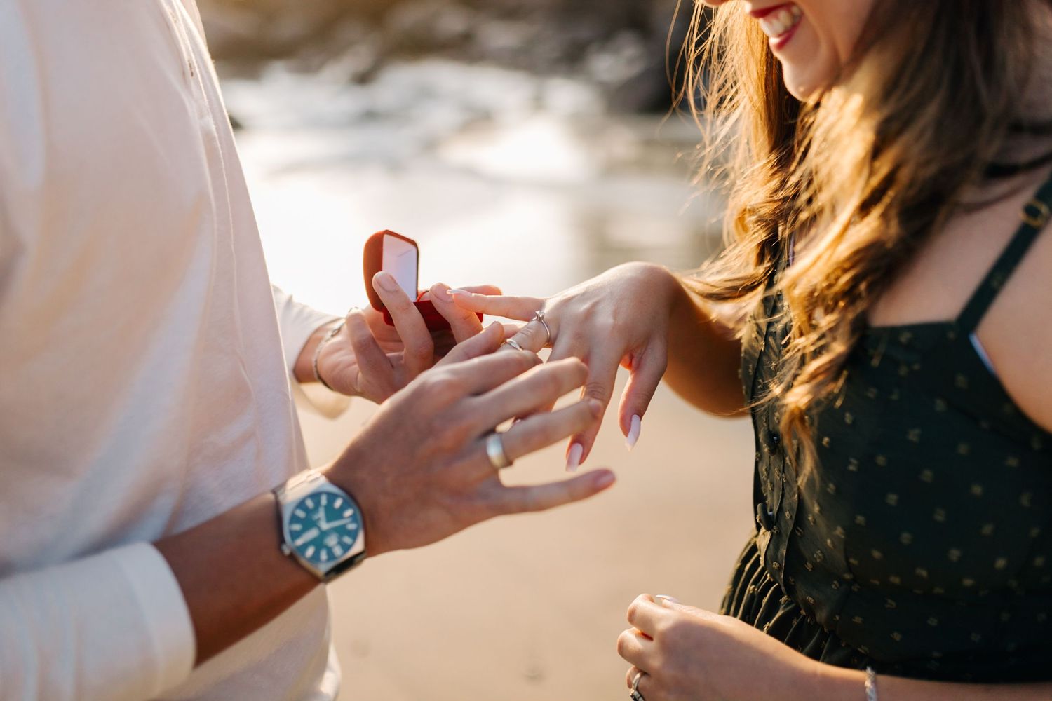 Close up of hands during a romantic beach proposal moment.