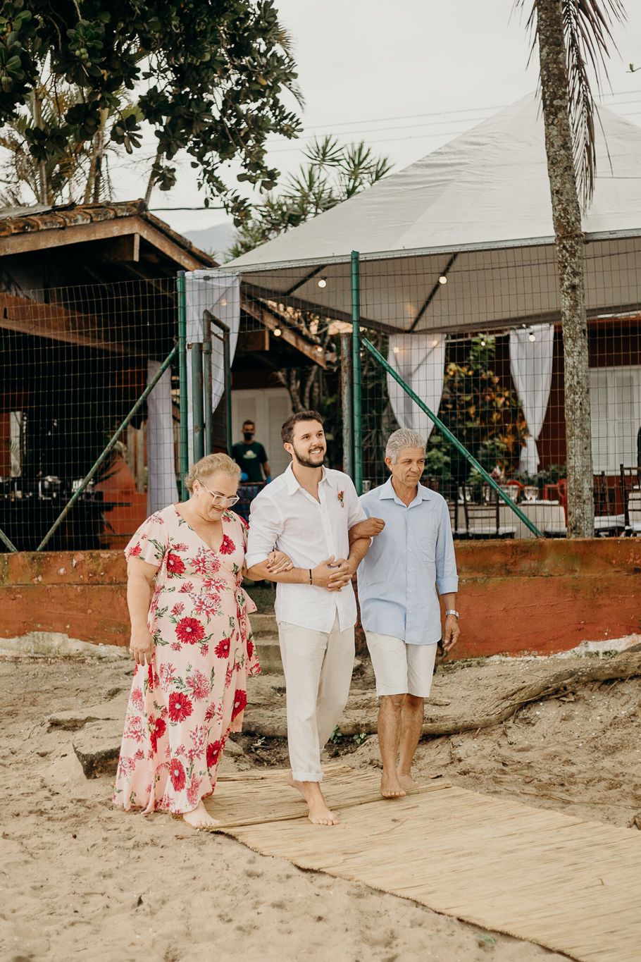Guests walking along a sandy pathway at an outdoor beach event.