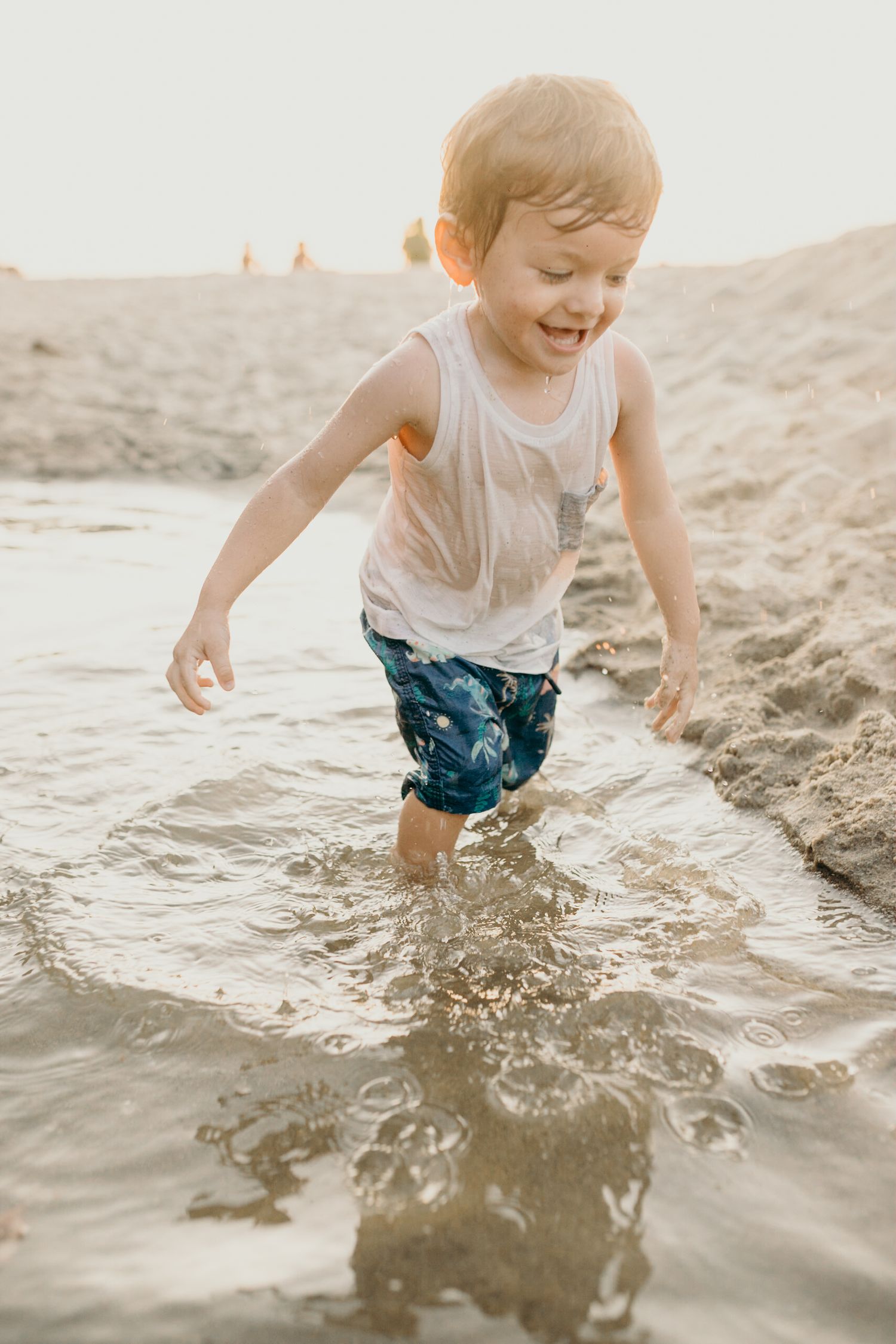 Happy child splashing and running through shallow water at the beach.