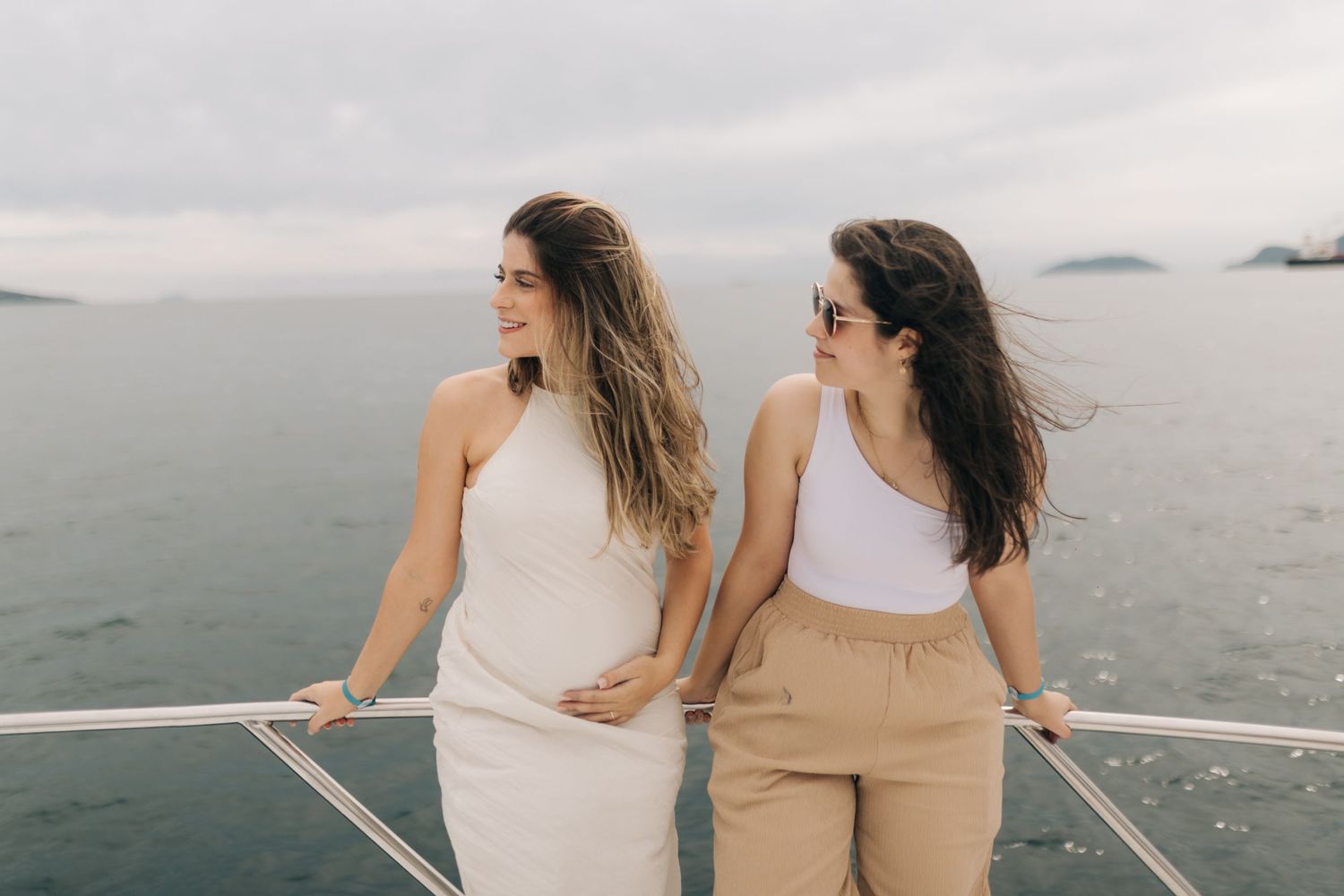 Friends posing on boat deck against overcast sky and ocean backdrop.