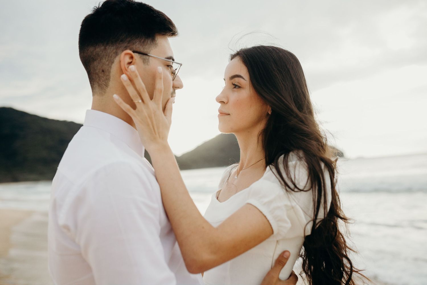 An intimate moment between a couple on a beach at sunset.