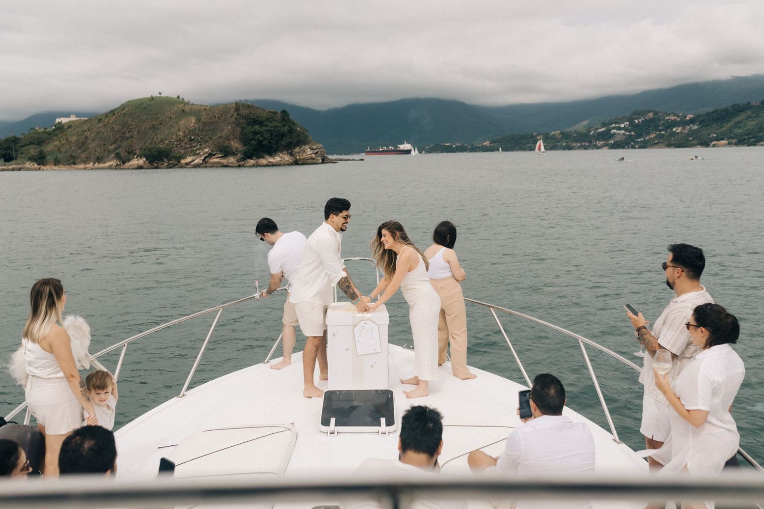 Group enjoying a leisure day on a boat deck overlooking coastal mountain scenery.