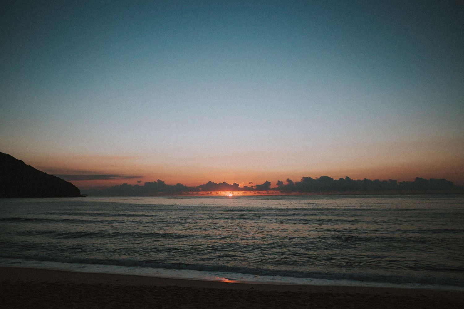Scenic ocean sunset with orange sky reflecting on calm waters.