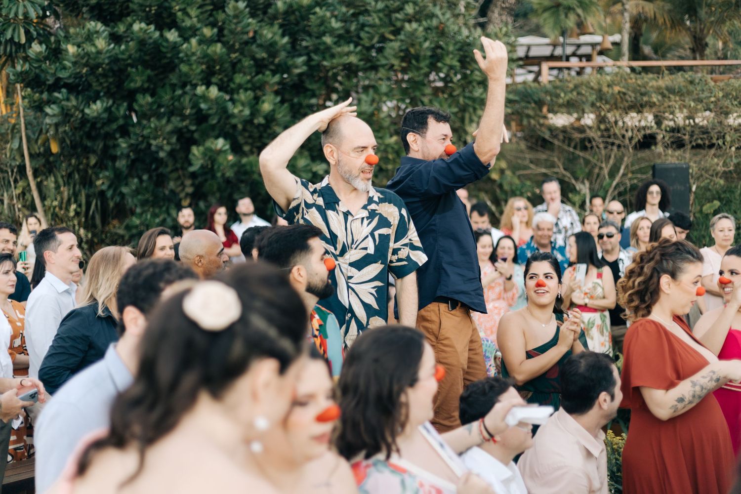Joyful wedding guests dance and celebrate at an outdoor reception.