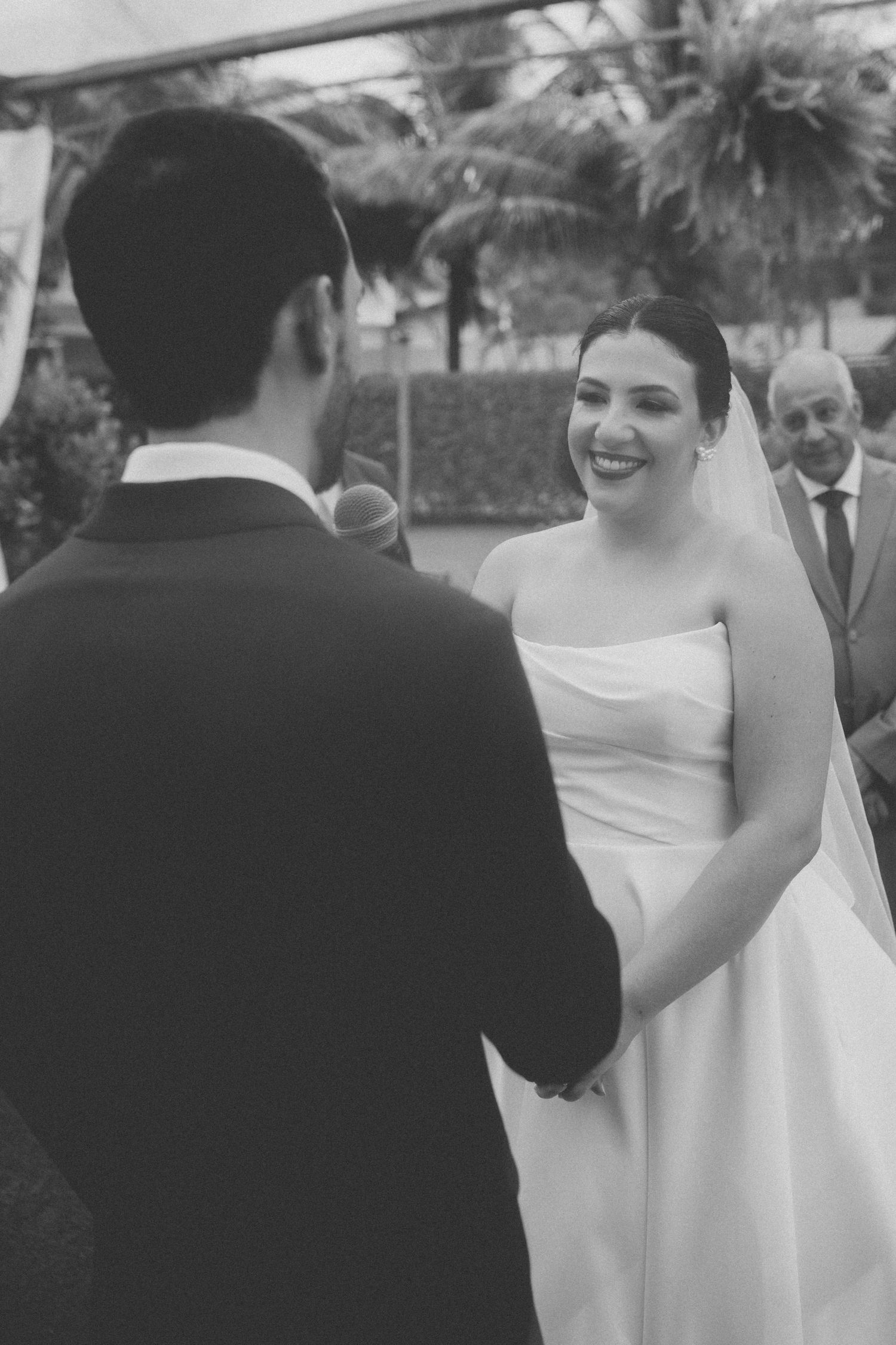 Black and white photograph of a wedding ceremony moment with palm trees in background.