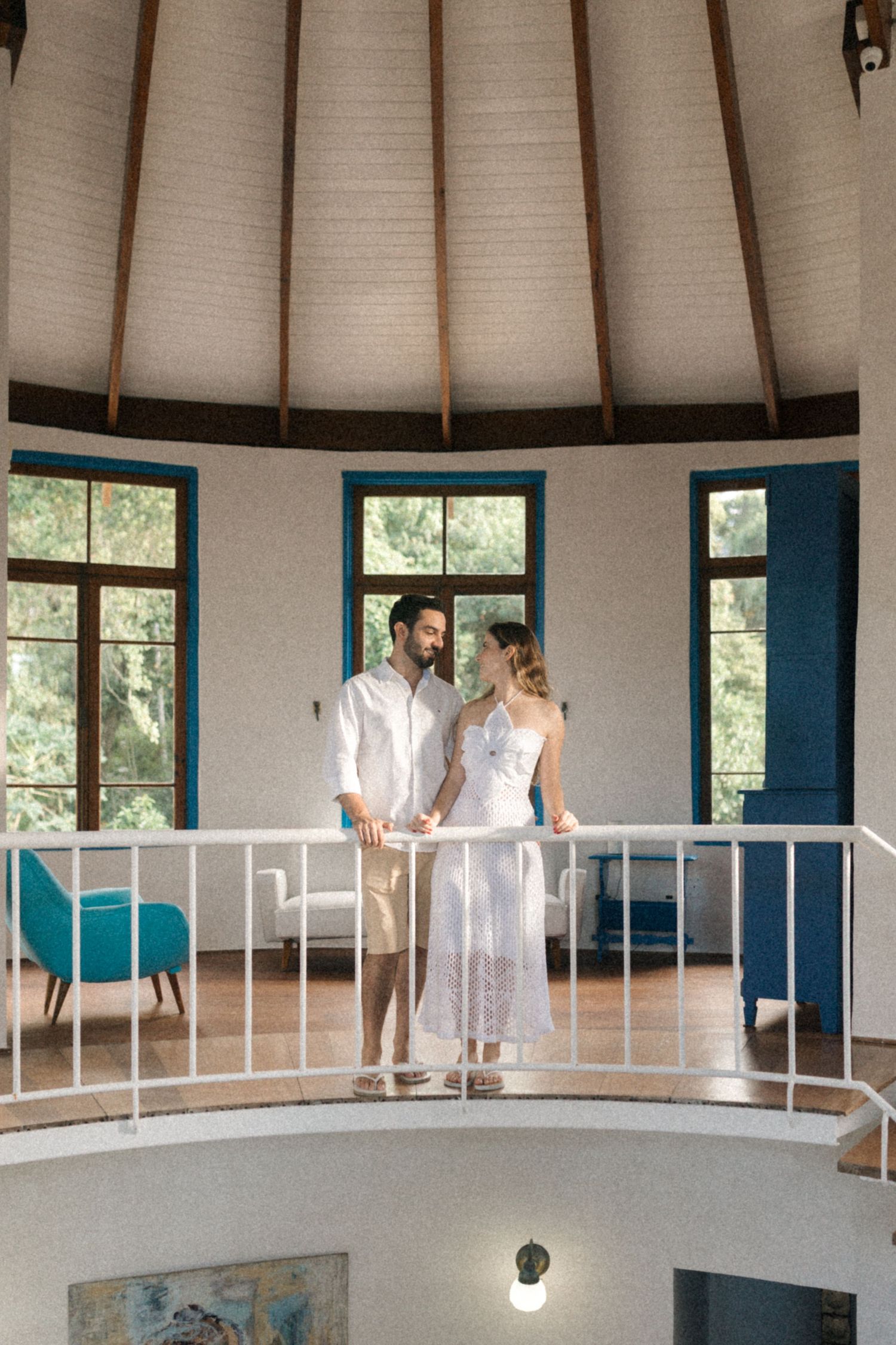 A couple enjoys a moment together on a curved balcony in a round room with turquoise accents.
