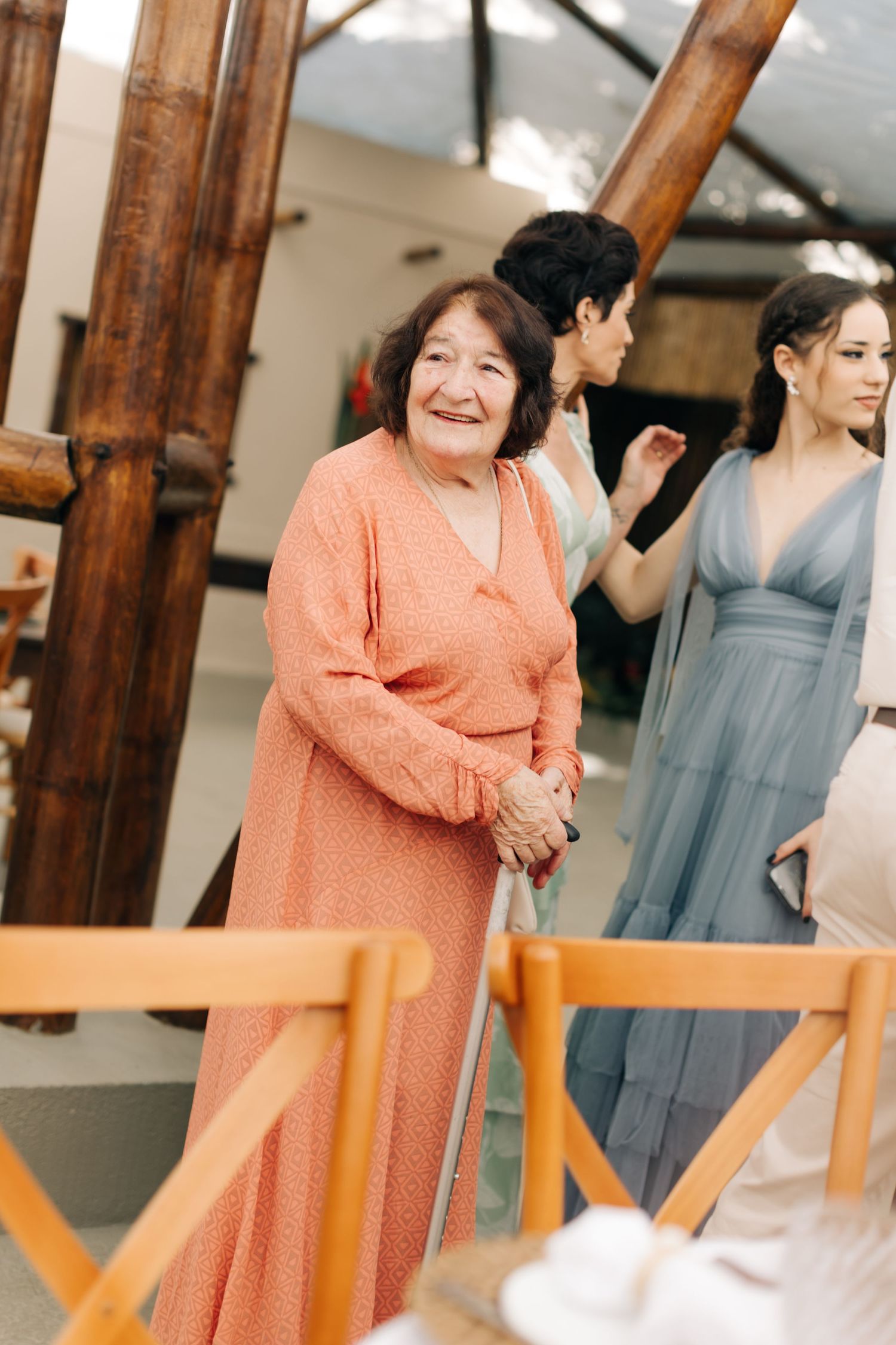 A group wearing formal attire stands together at a special occasion with wooden beams visible.