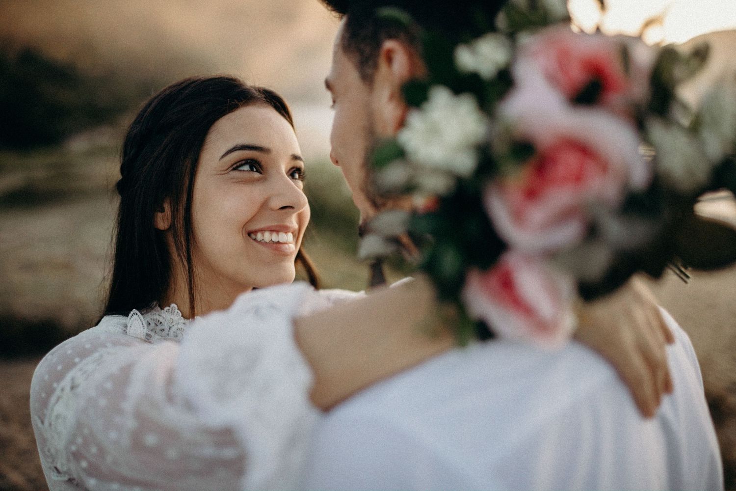 Close-up romantic moments with pink florals in coastal setting.