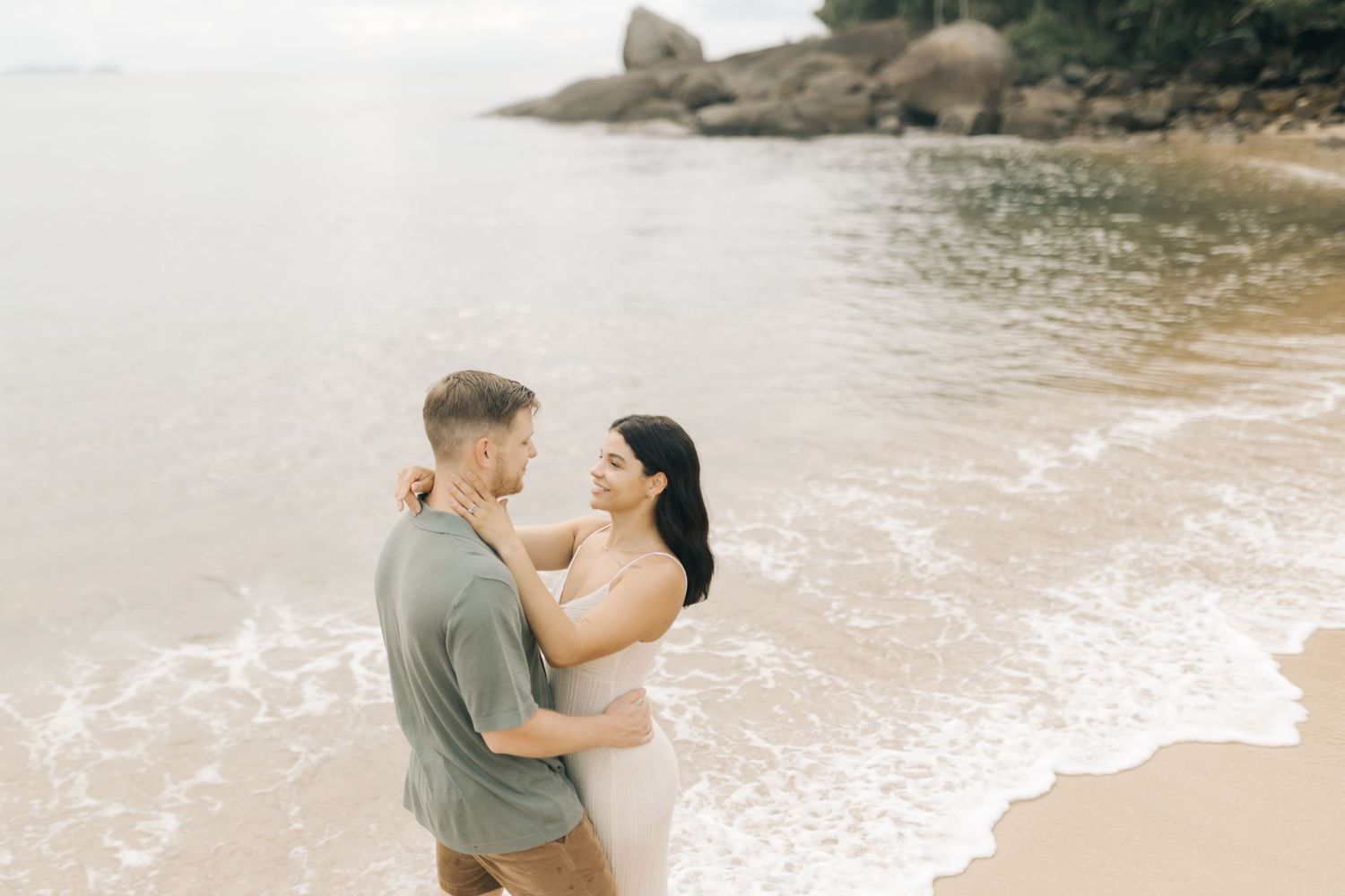 A romantic beach photoshoot capturing an intimate moment between a couple near the ocean.
