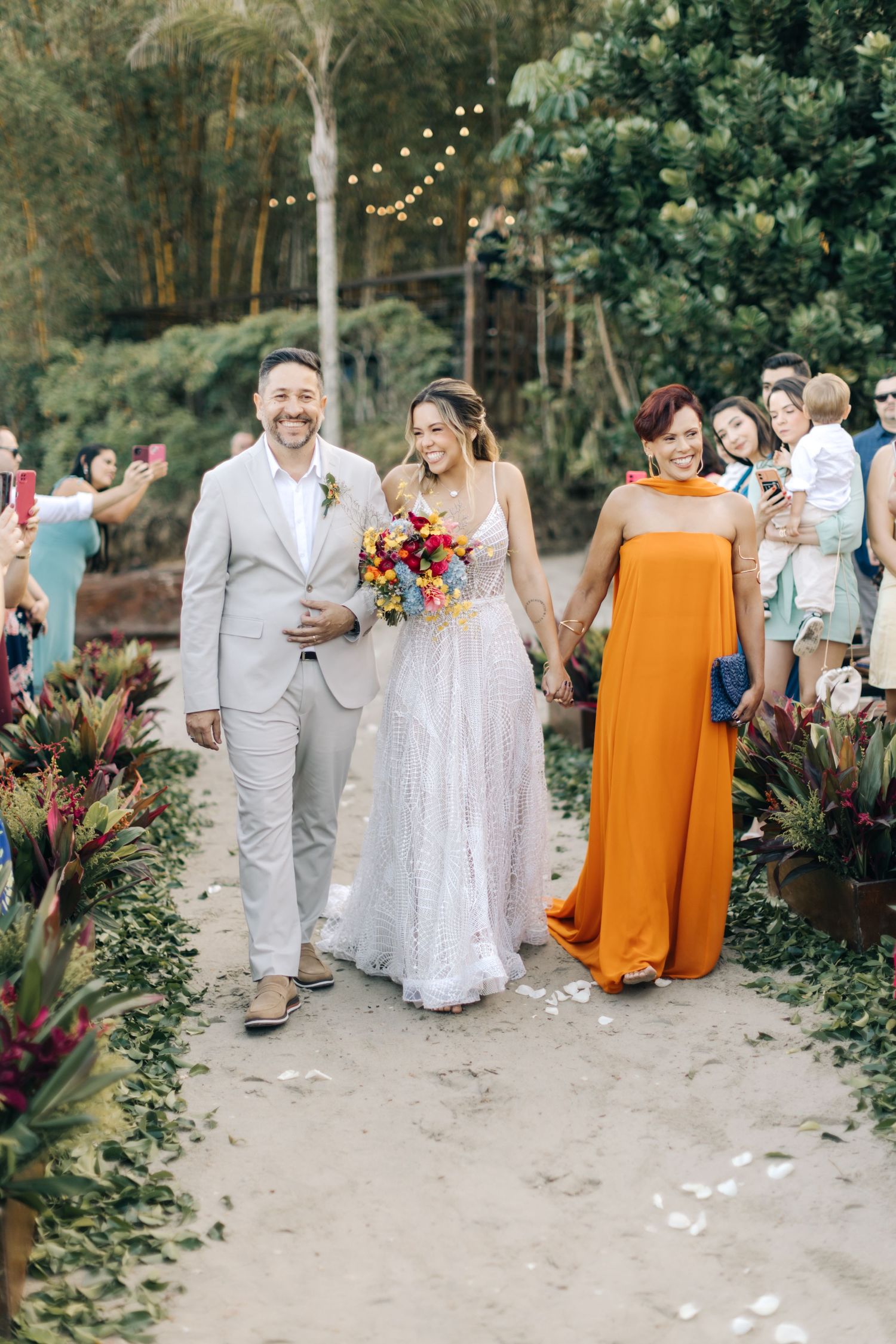 Wedding party walking and celebrating on garden path with tropical greenery.