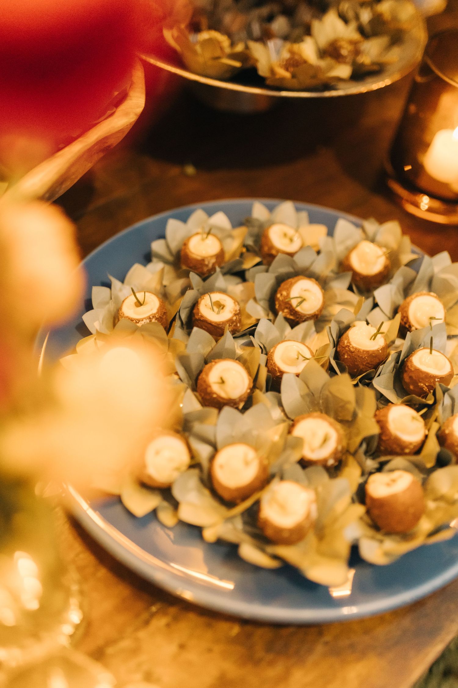 Elegant wedding desserts displayed on a blue plate garnished with delicate paper wrappers.