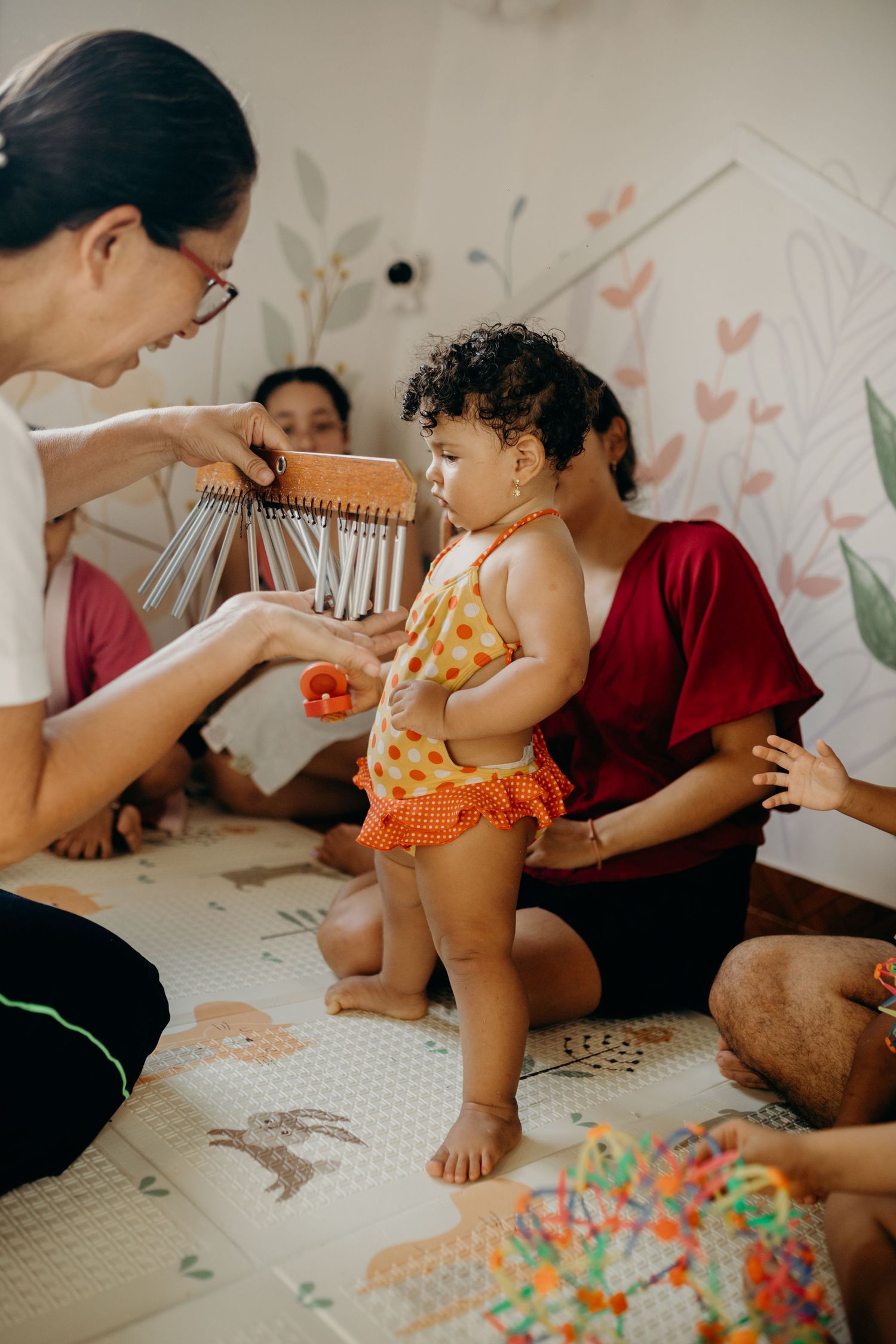 A colorful music therapy session with a toddler standing in an orange outfit as chimes are shown.