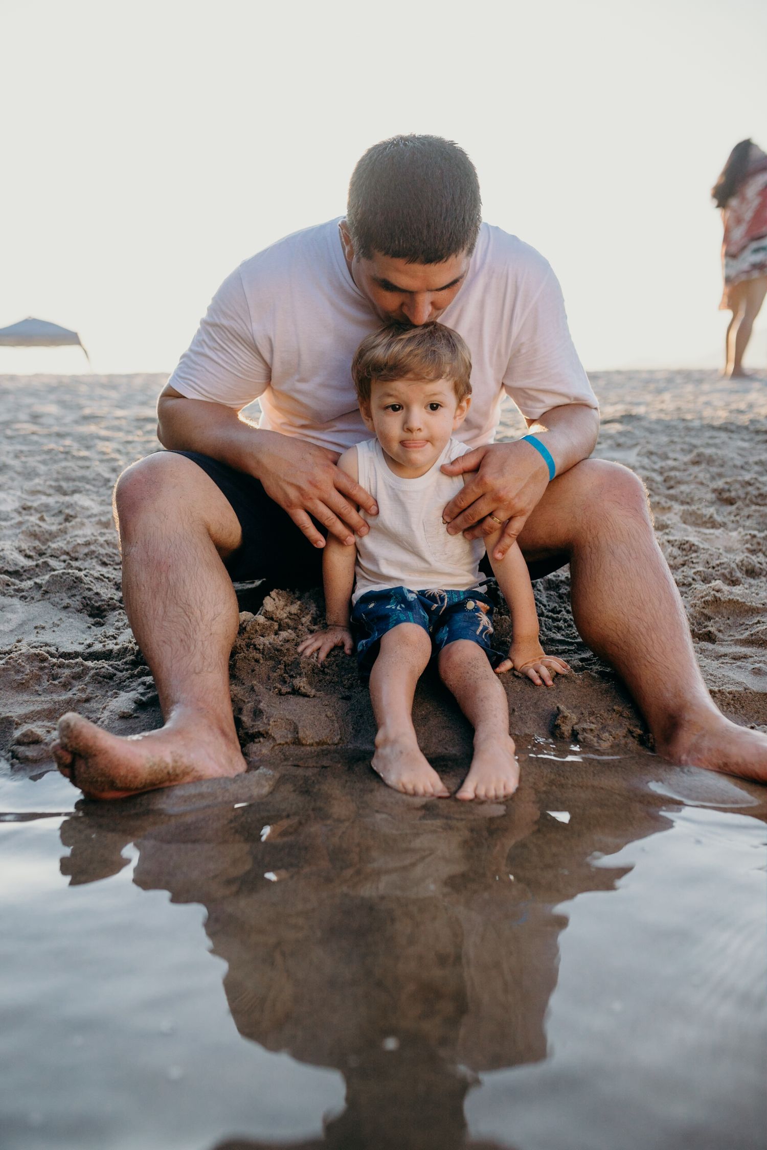 Sweet moment shared at water's edge on rocky beach during sunset.