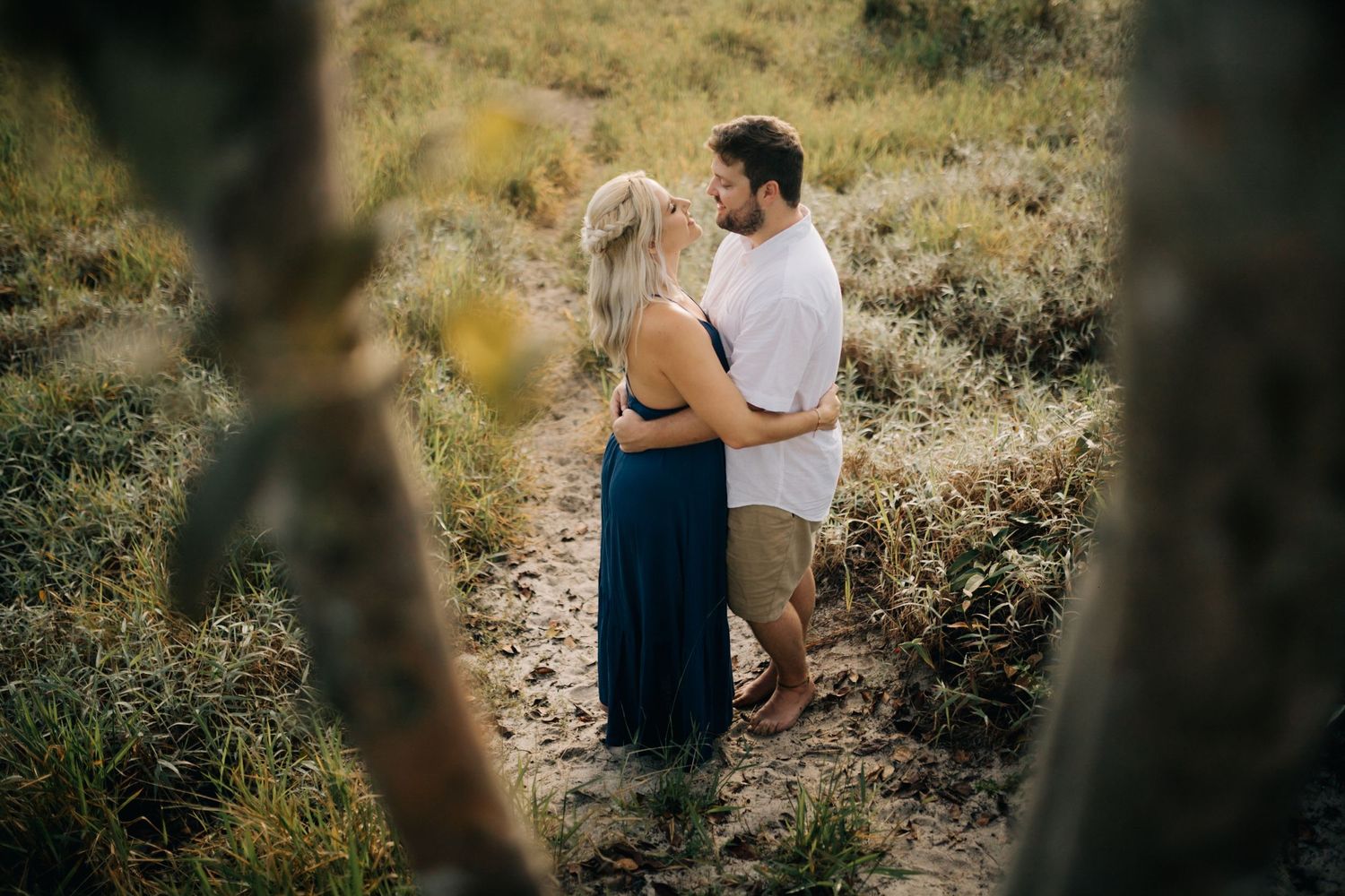 Two people walking on a grassy hillside path with mountains in the background.