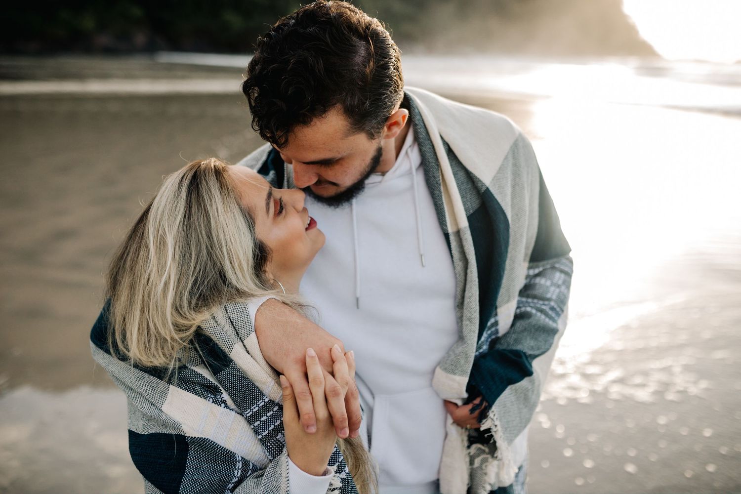 Two people embrace passionately on a serene beach at sunset.