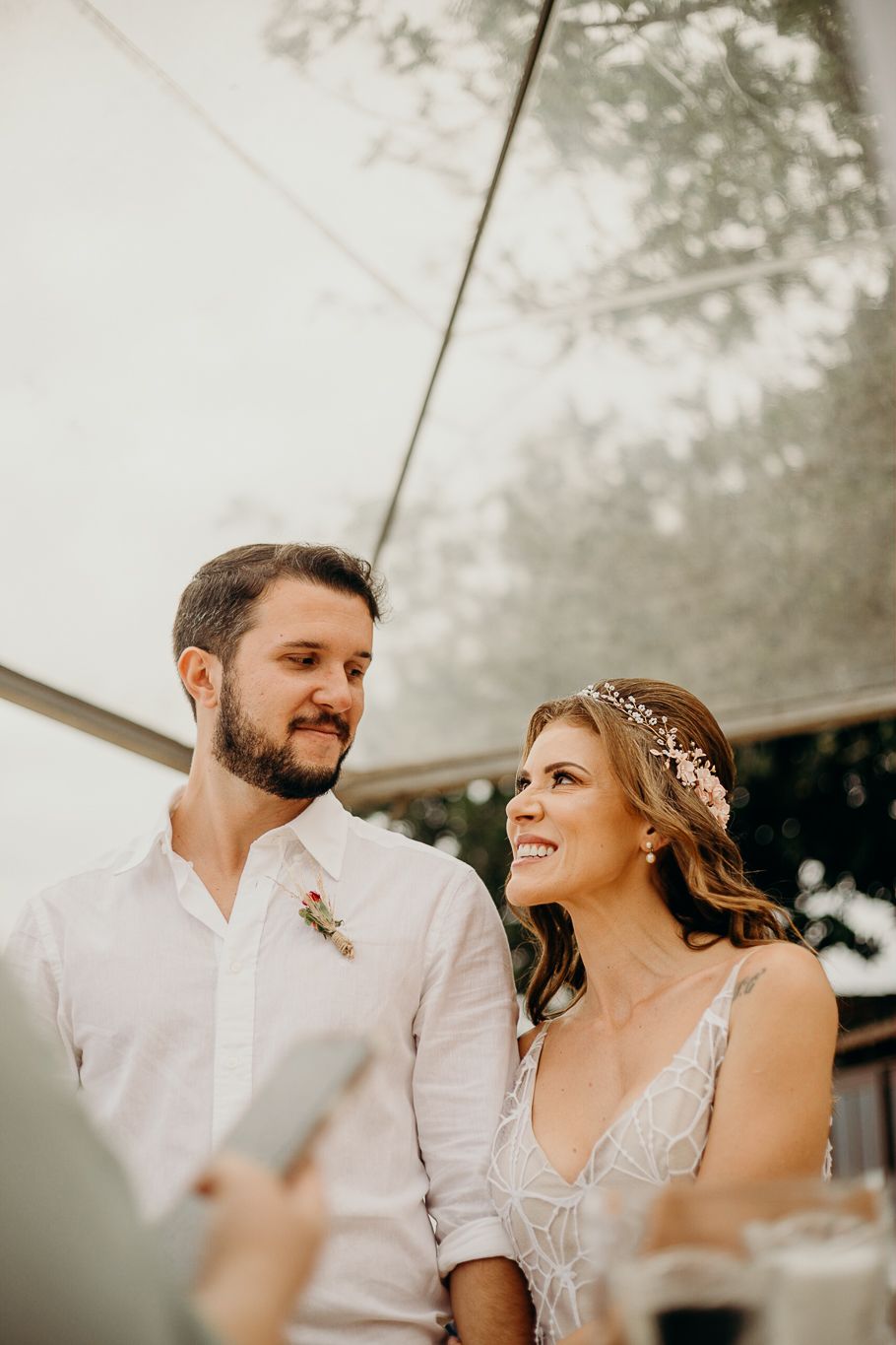 Candid reception photo showing couple laughing together under outdoor tent.