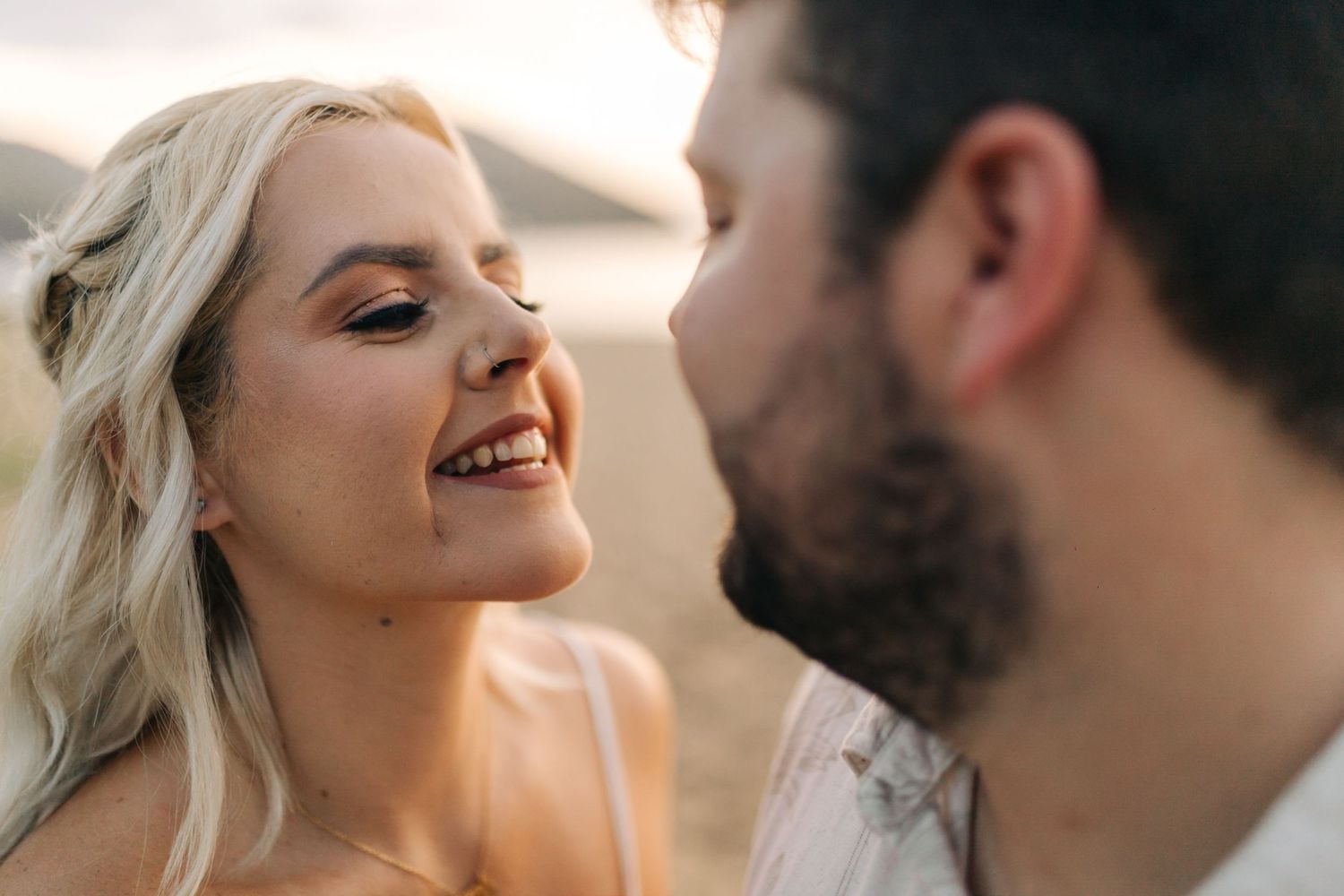 A candid moment of laughter and joy between a couple during their beach photoshoot.