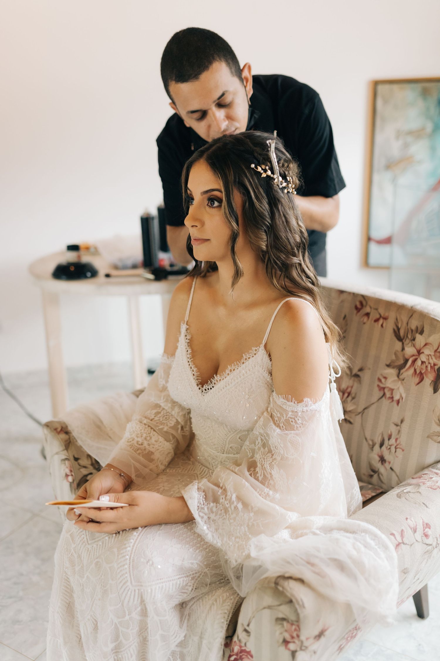 Hair styling session during wedding preparations in an elegant white room.