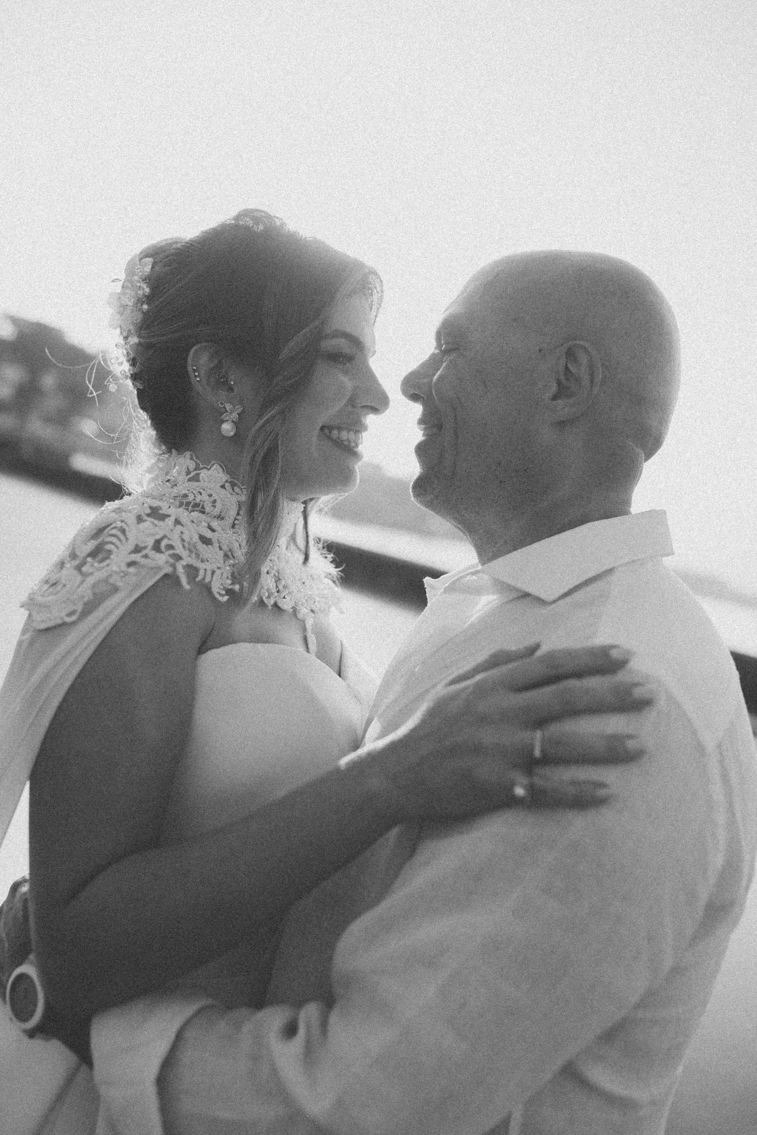 A black and white candid photo capturing a joyful moment between newlyweds.