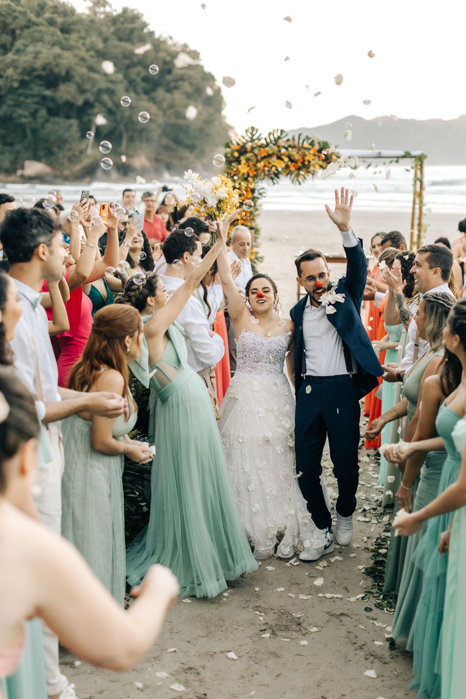 Festive beach wedding celebration with guests tossing confetti around the wedding party.