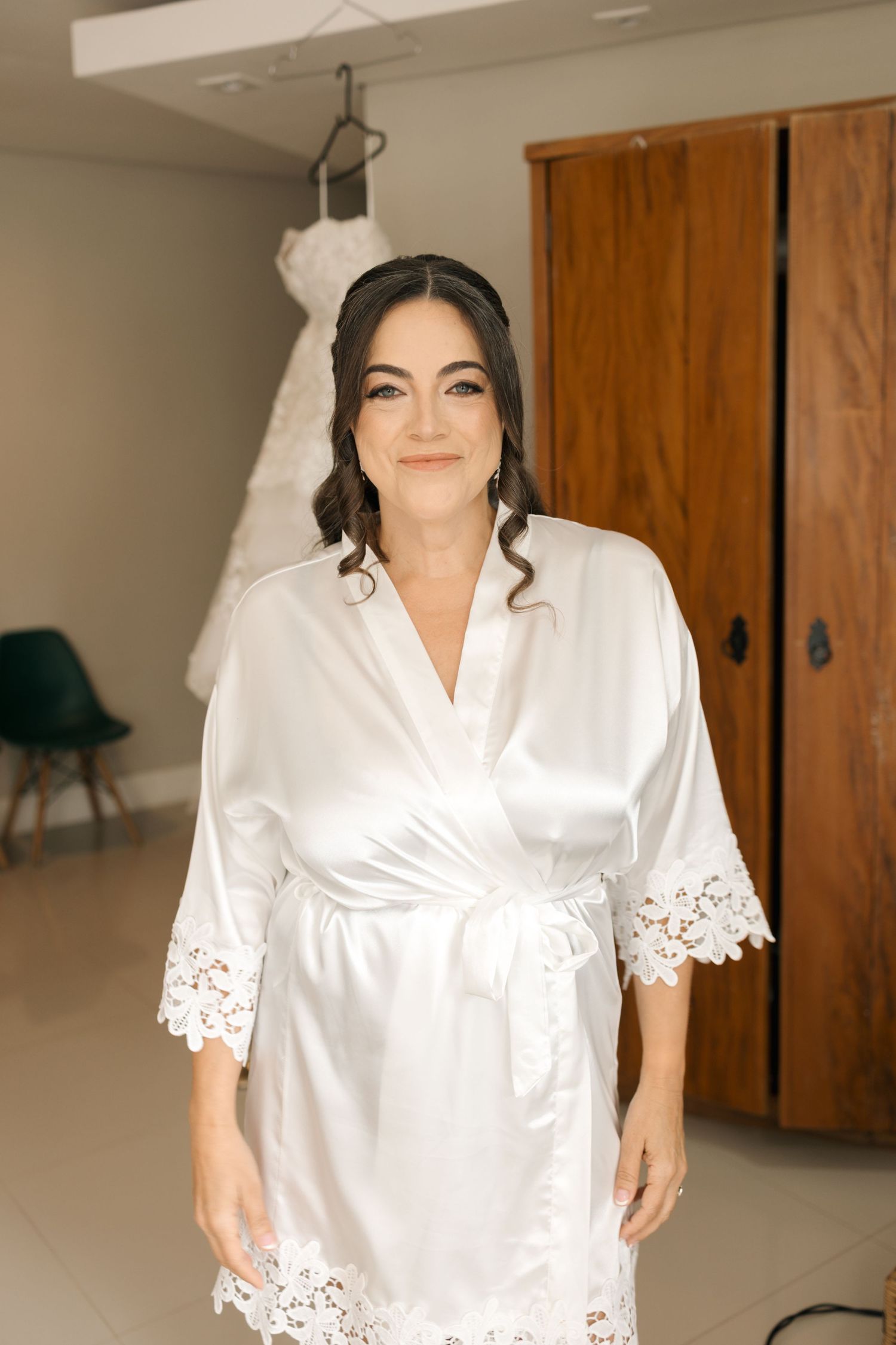 White satin robe with delicate lace trim detail worn during preparation.