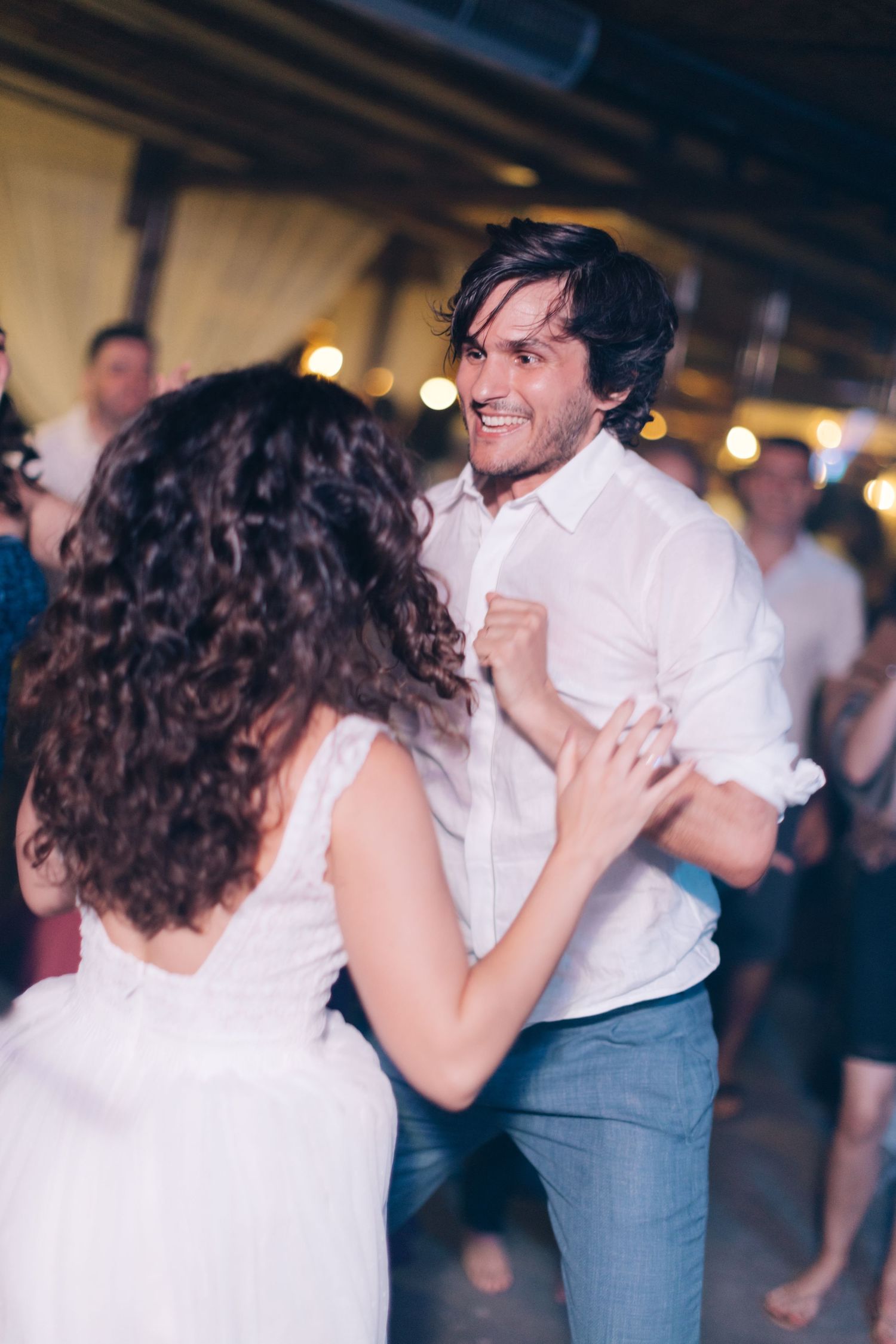 A joyful couple dances together at a wedding reception with soft lighting.
