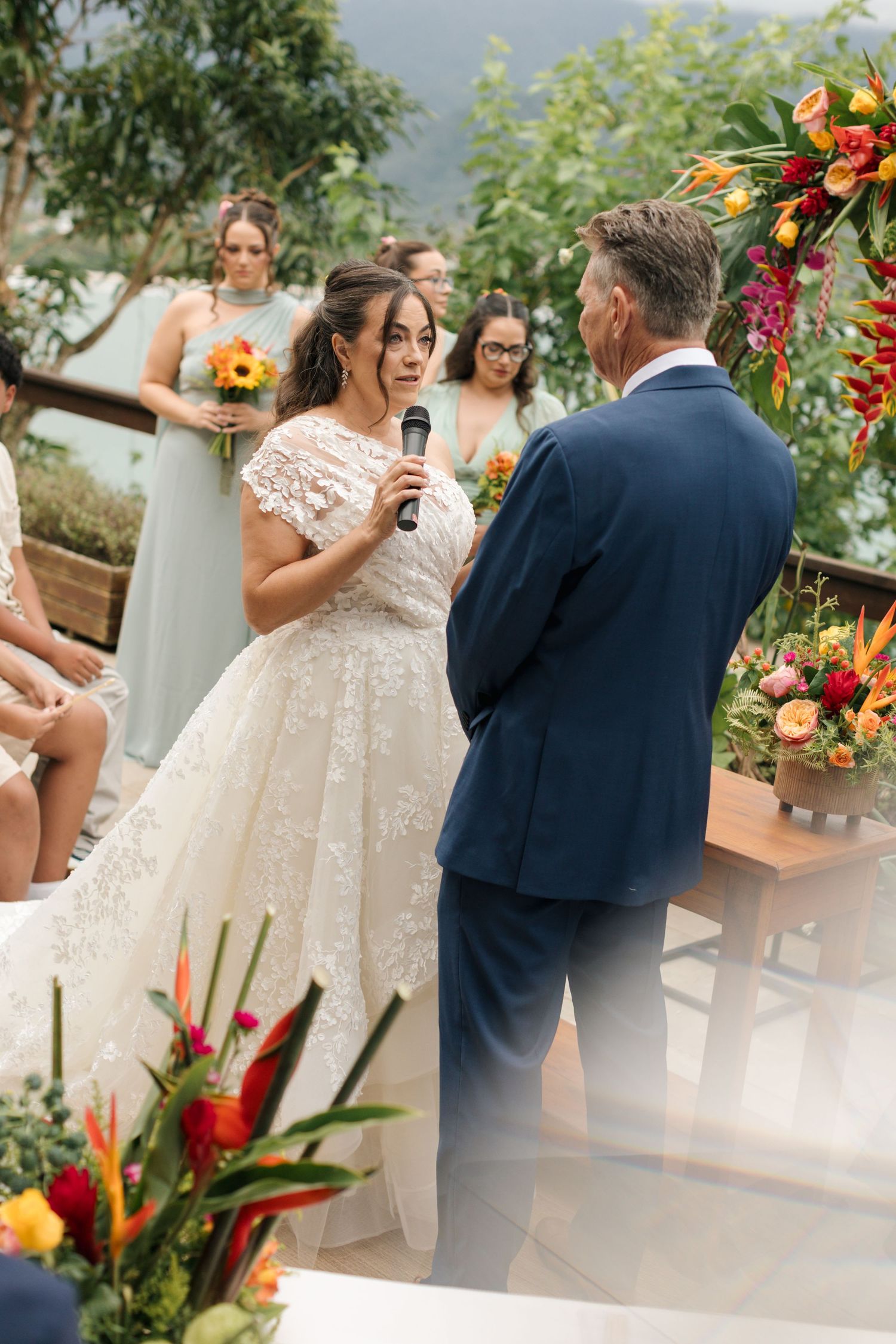 Wedding ceremony with vibrant tropical flower arrangements and mountain backdrop.