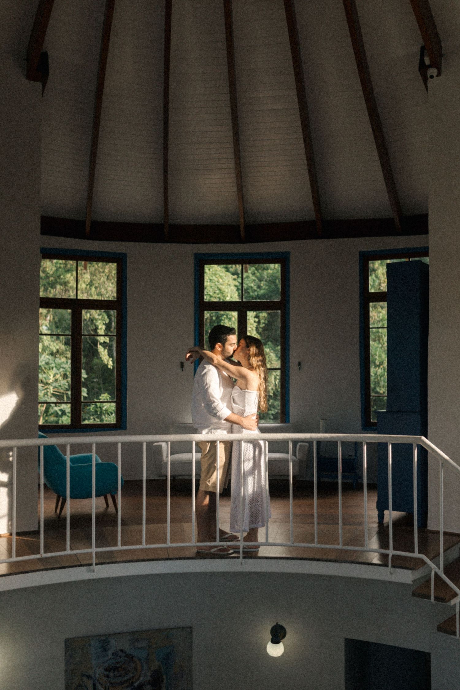 Couple embracing in a bright circular room with white walls and blue-trimmed windows.