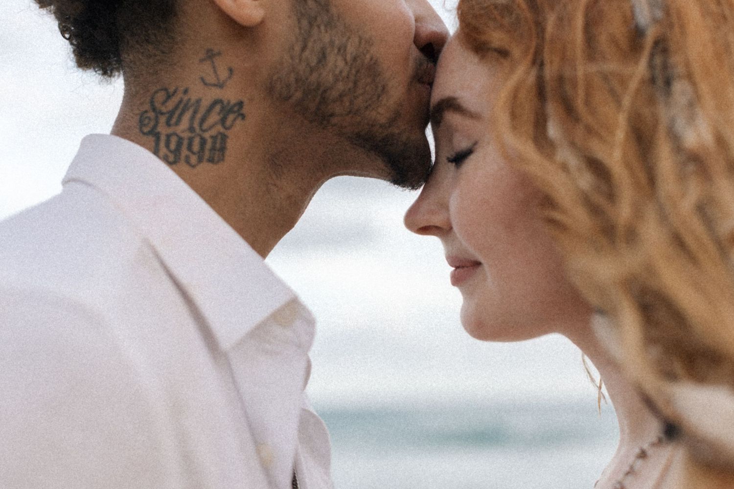 An intimate close-up portrait of a couple sharing a romantic moment by the ocean.