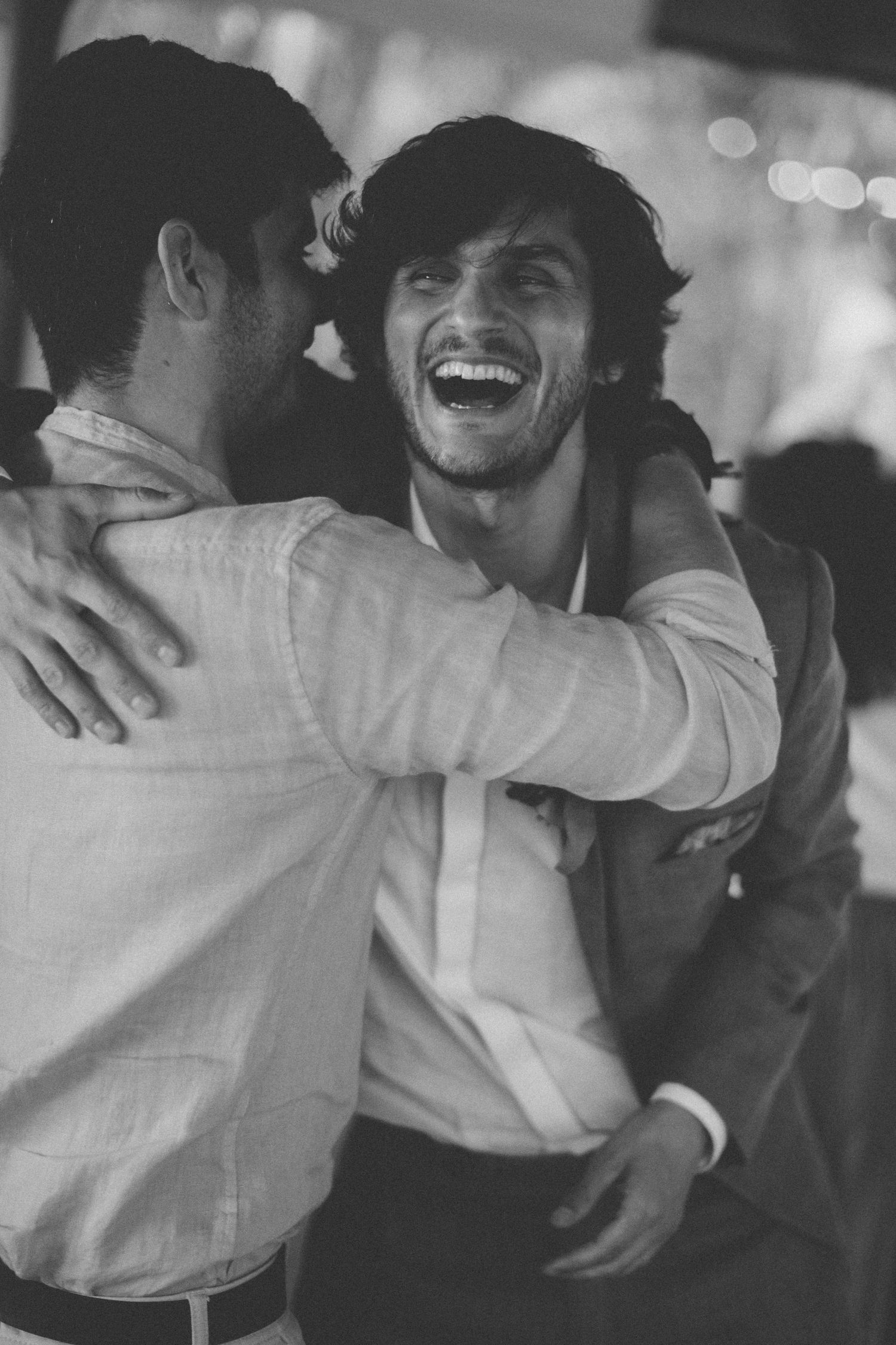Black and white photo captures candid embraces at a celebratory gathering.