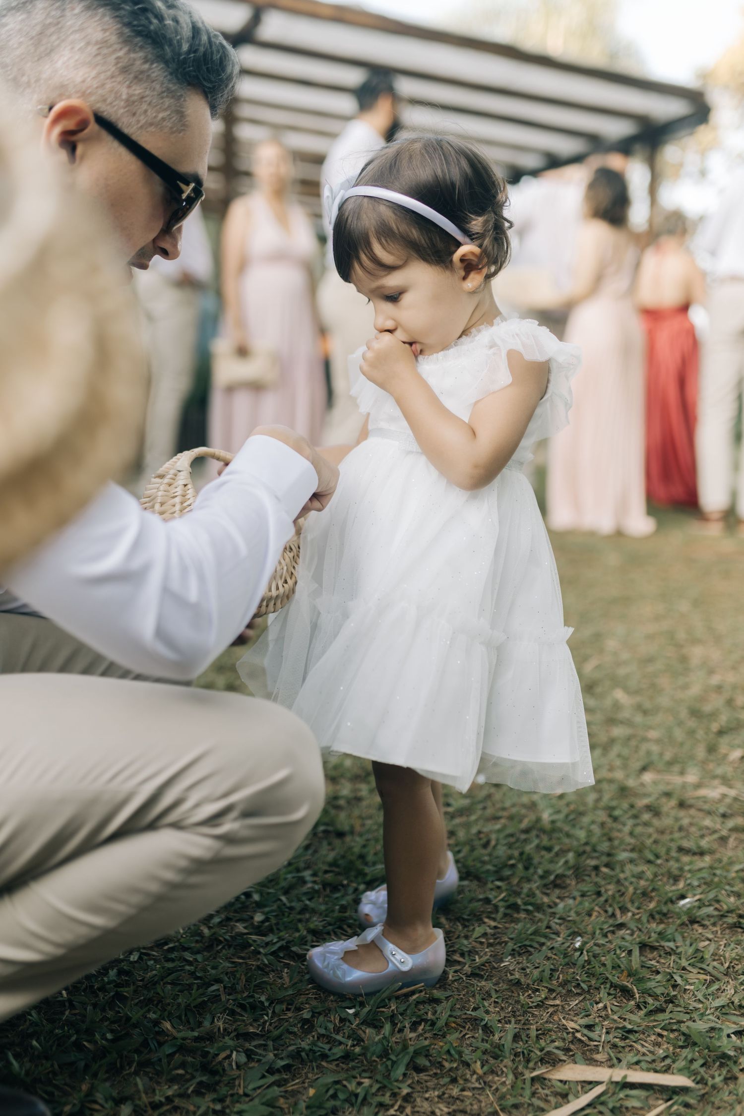 A tender moment at an outdoor wedding with a small child in white dress.
