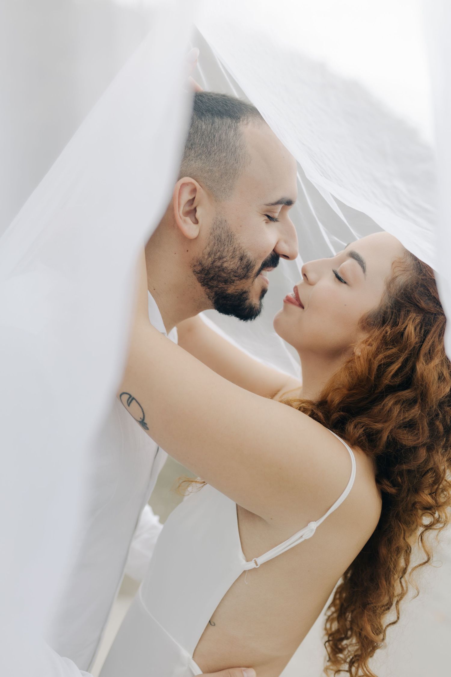 Dreamy wedding portrait with soft lighting as couple embraces under veil.