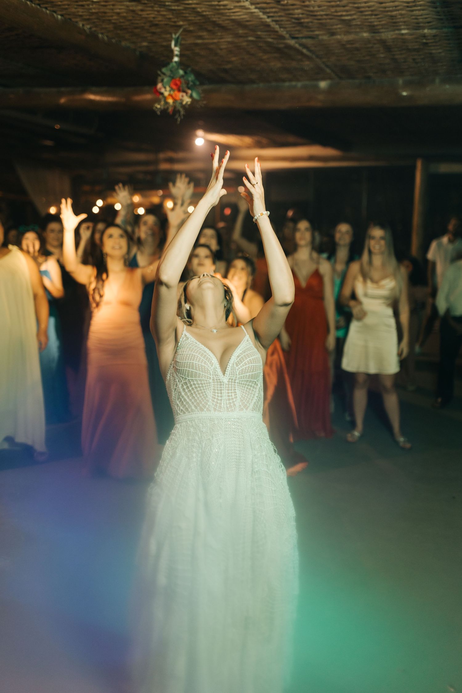 Wedding reception dance floor scene with a bride in white dress celebrating under colorful lights.