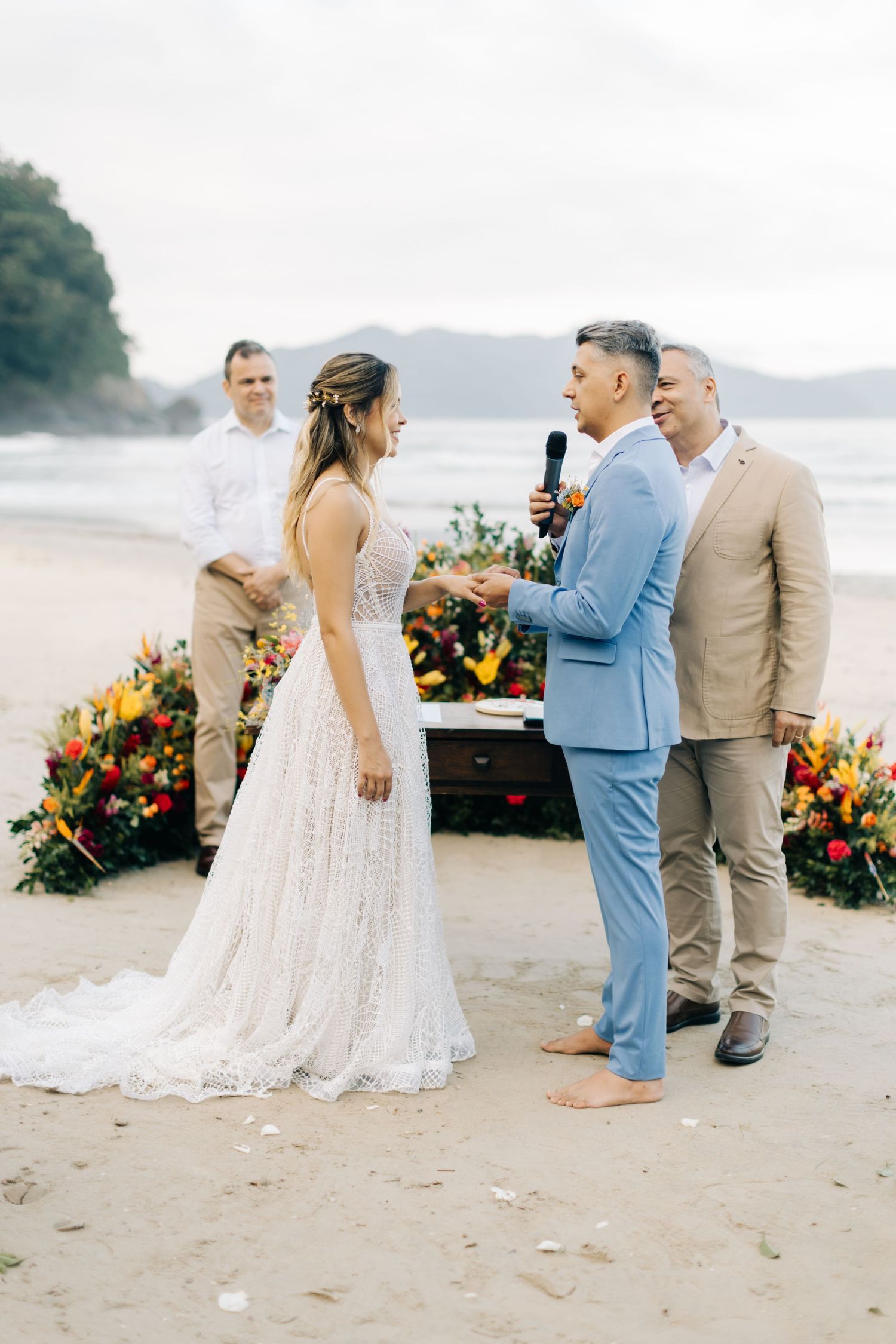 A beachside wedding ceremony with an elegant floral arrangement and a couple exchanging vows near the ocean.