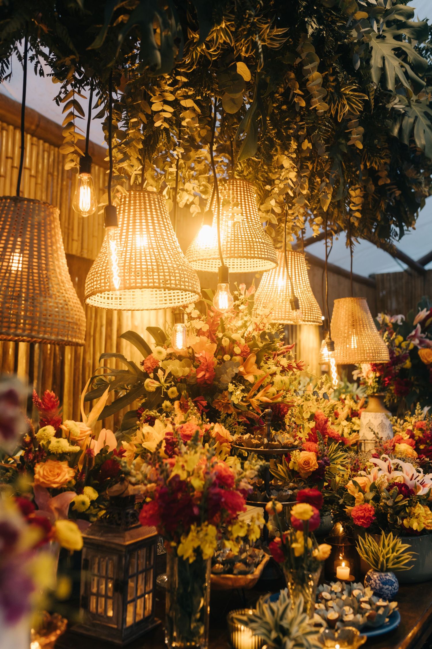 Romantic wedding reception decor with woven pendant lights and colorful floral arrangements.