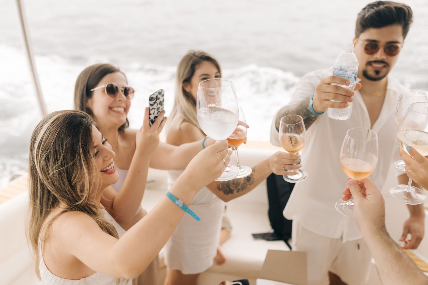 Group of friends raising glasses in a celebratory toast on a yacht.