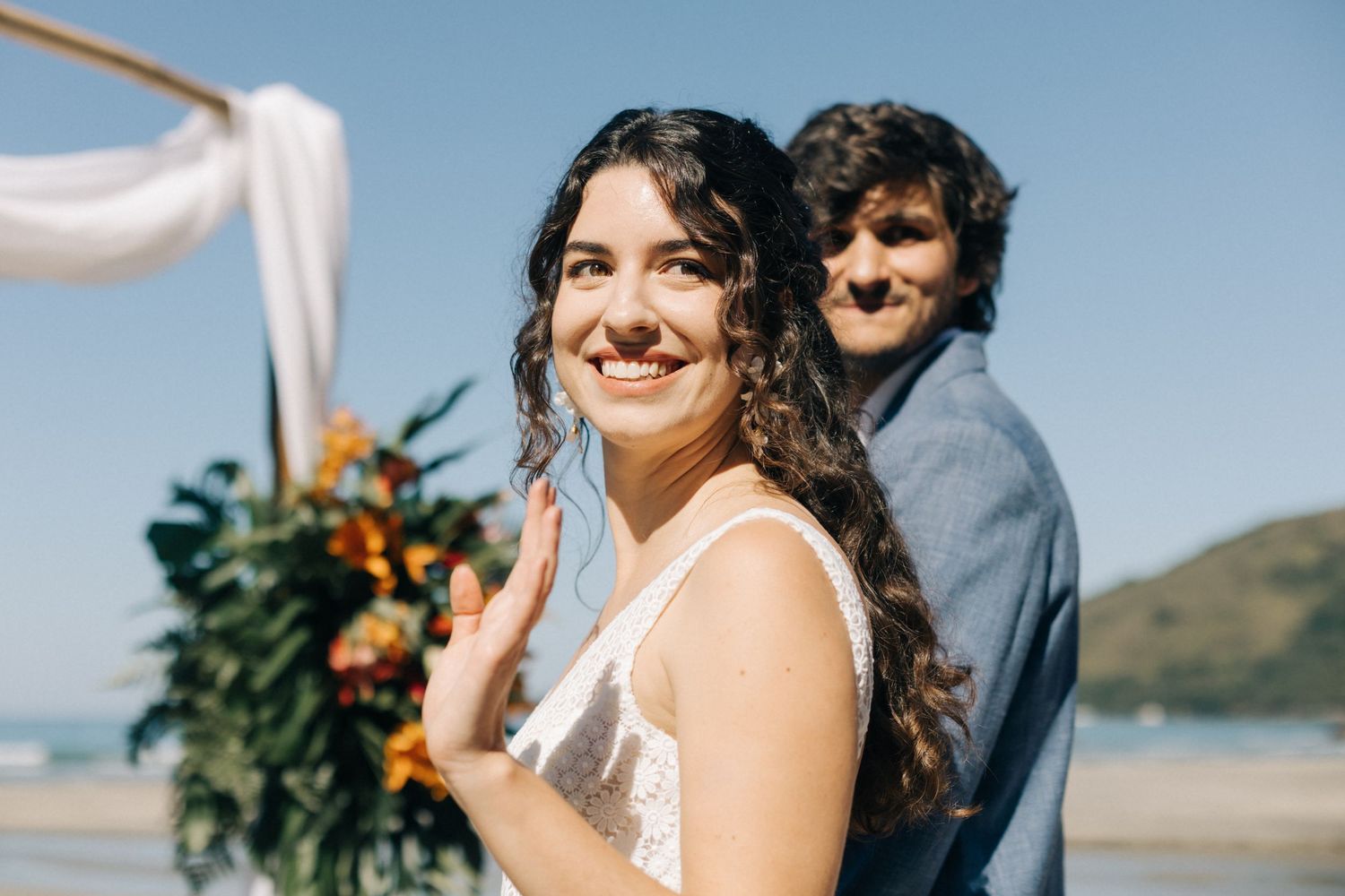 Beachside wedding ceremony with tropical floral arch and ocean backdrop.