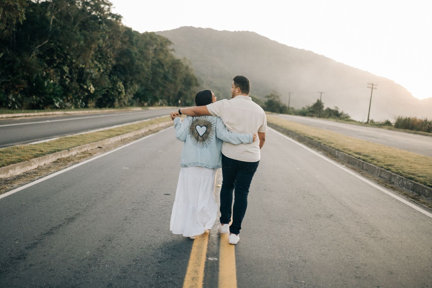 Couple walking away on an empty mountain road during golden hour.