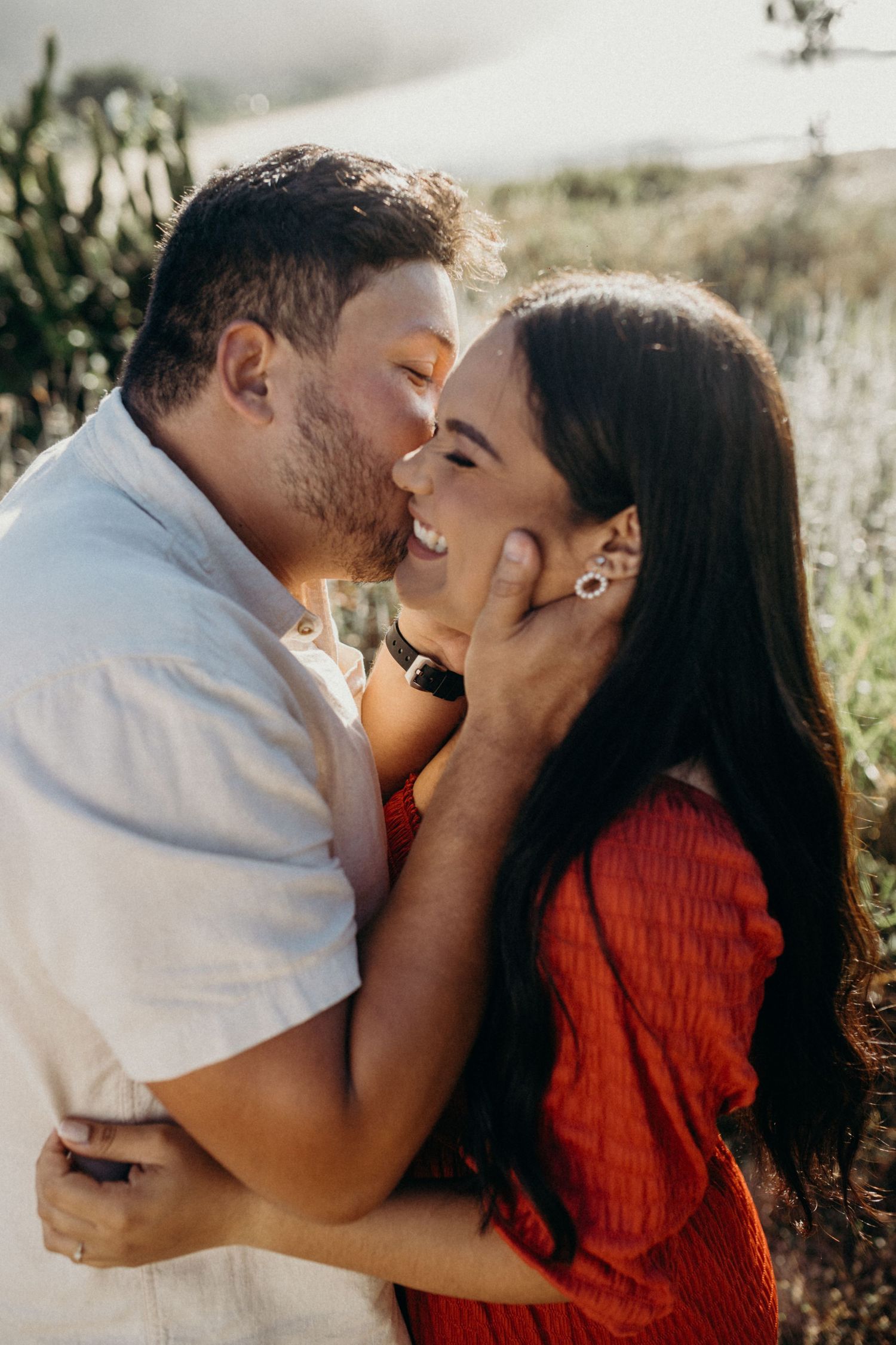 Couple sharing passionate moment on mountain trail during sunset photo session.