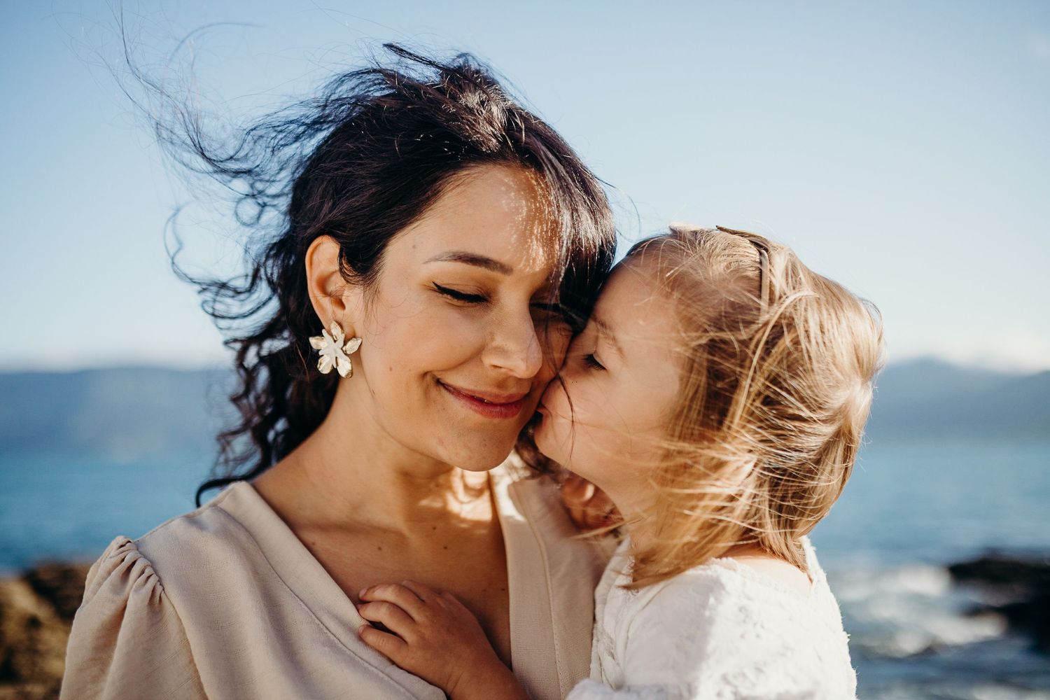 Tender moment captured between parent and child on scenic coastal rocks.
