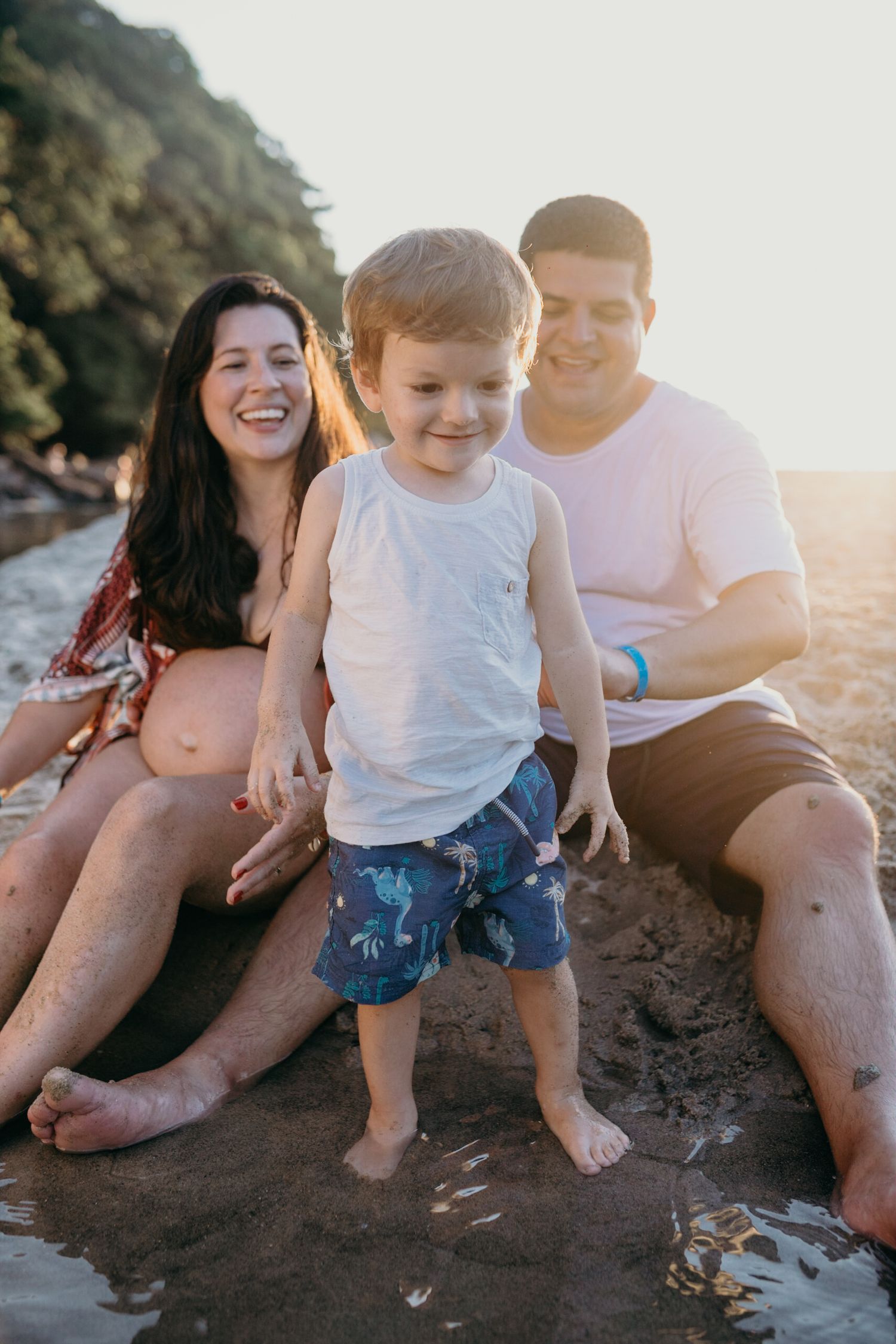 Joyful family moment captured on rocky beach during sunset.